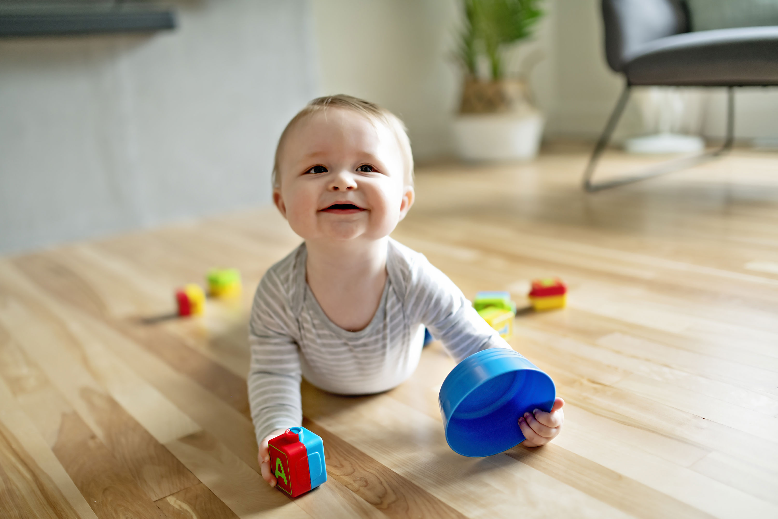 Beby der ligger på et gulv og leger med klodser