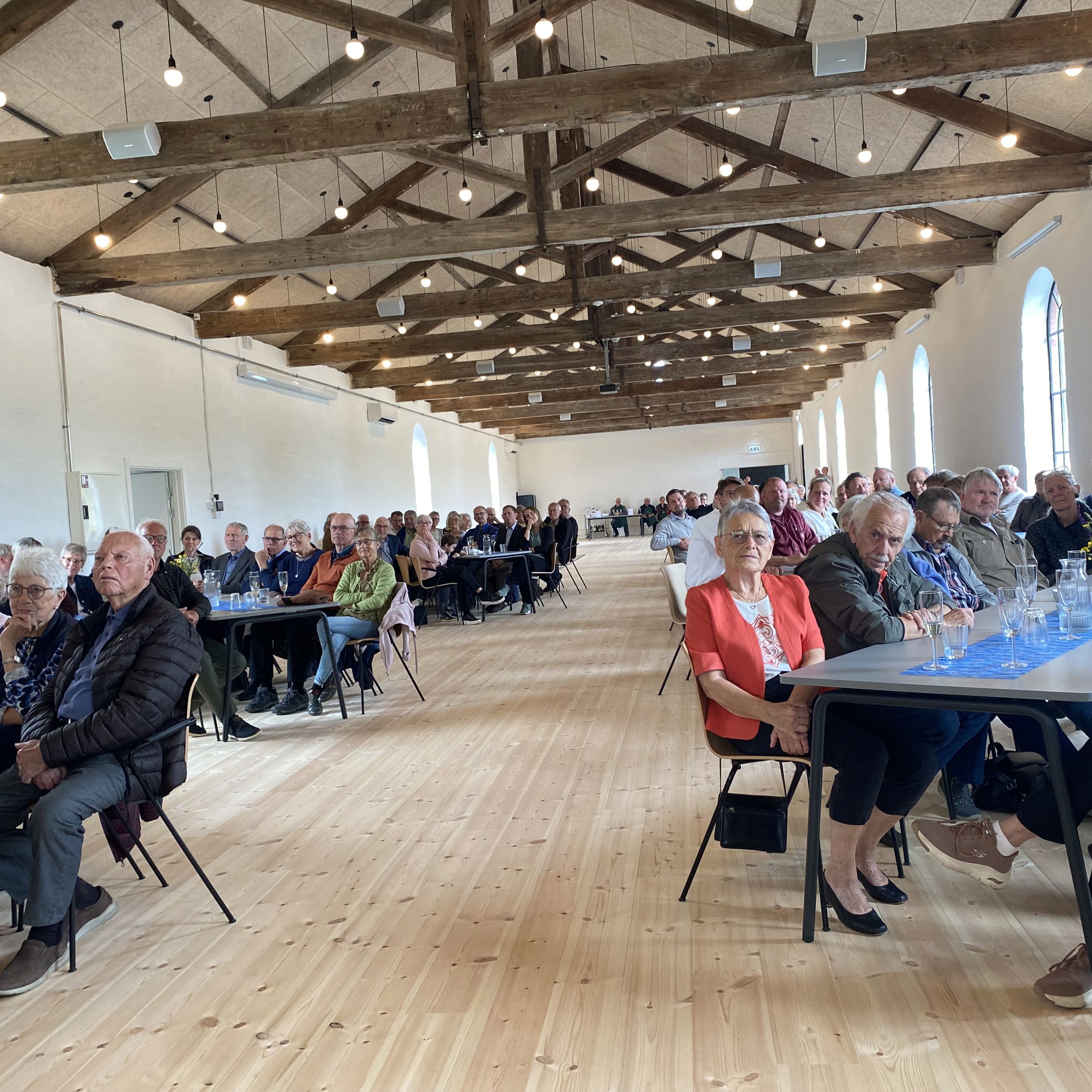 Mennesker sidder ved borde i en stor sal