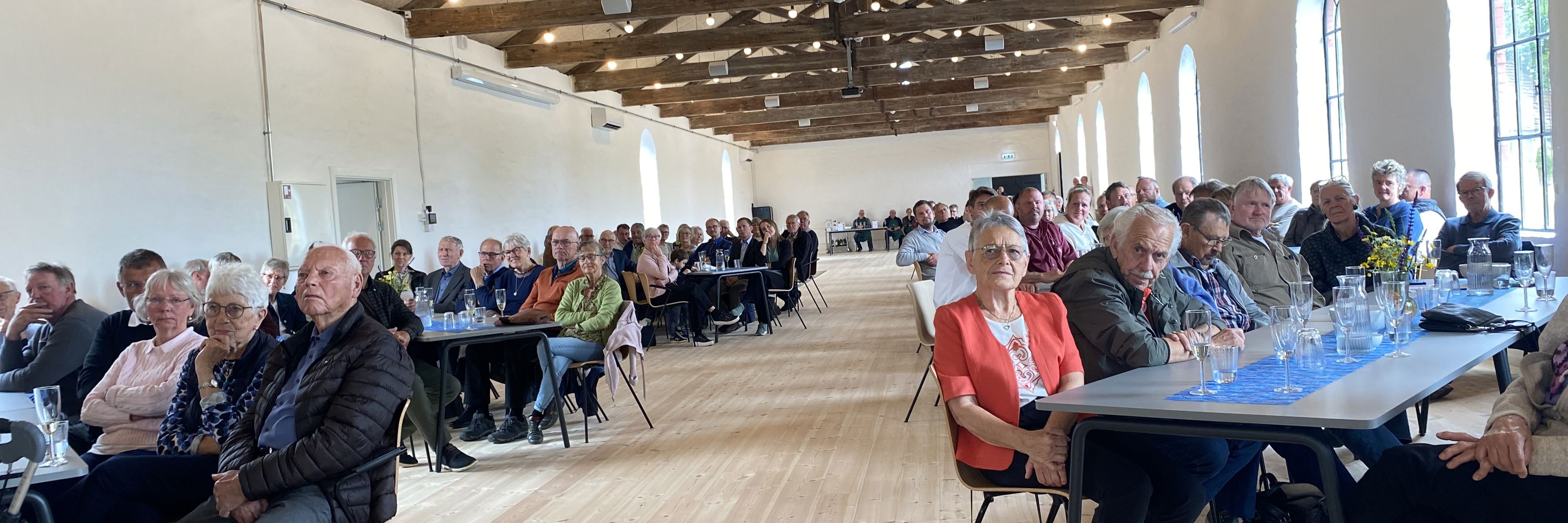 Mennesker sidder ved borde i en stor sal