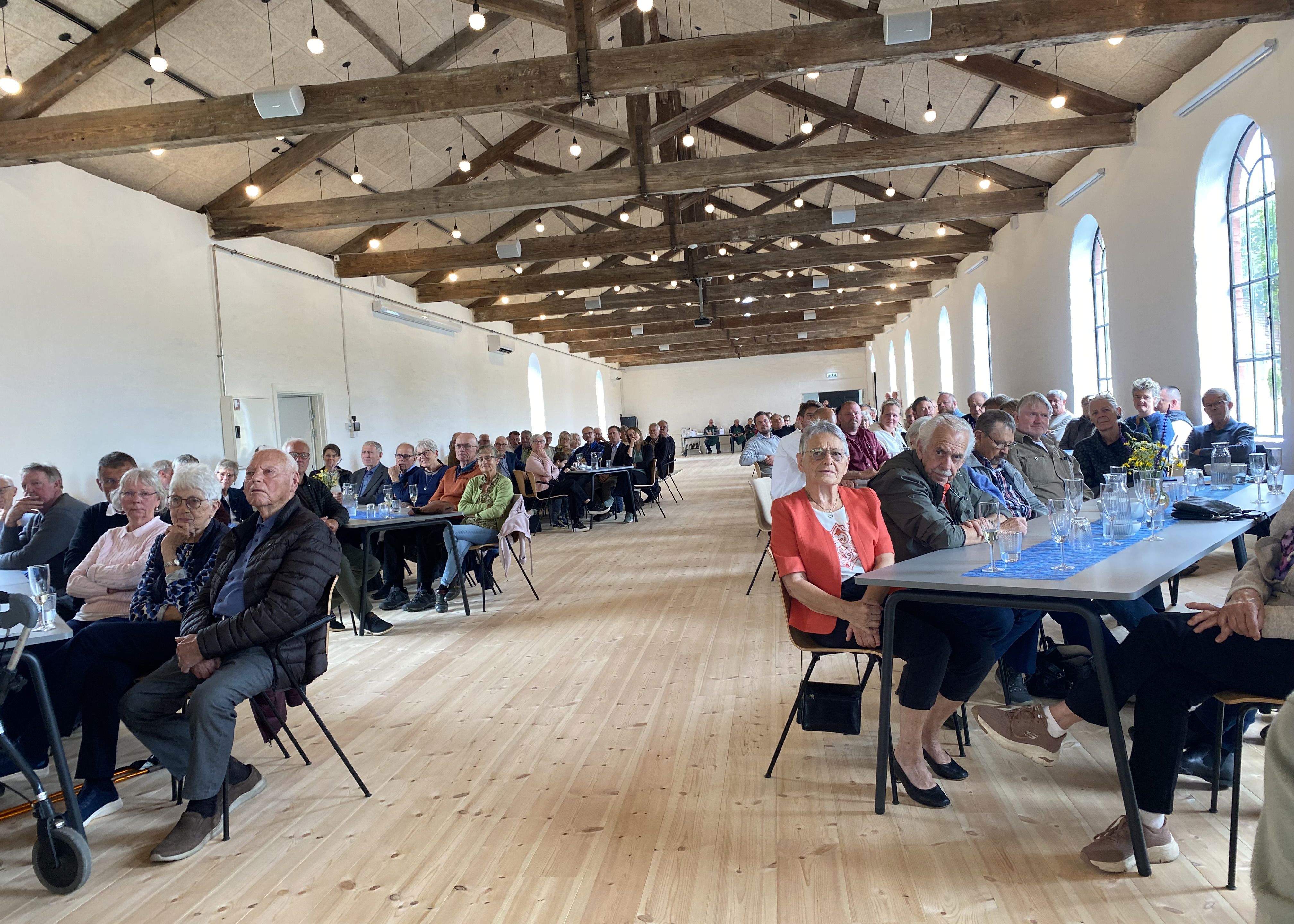 Mennesker sidder ved borde i en stor sal