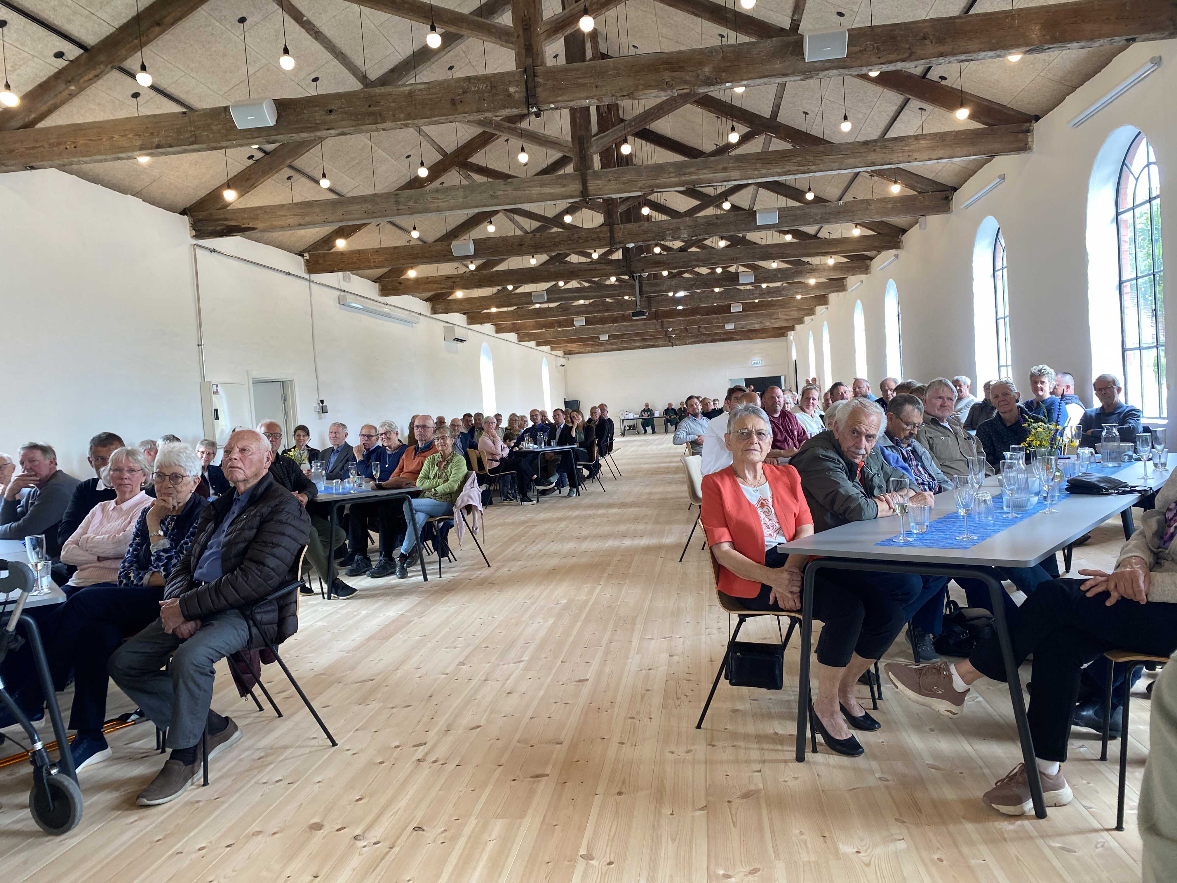 Mennesker sidder ved borde i en stor sal