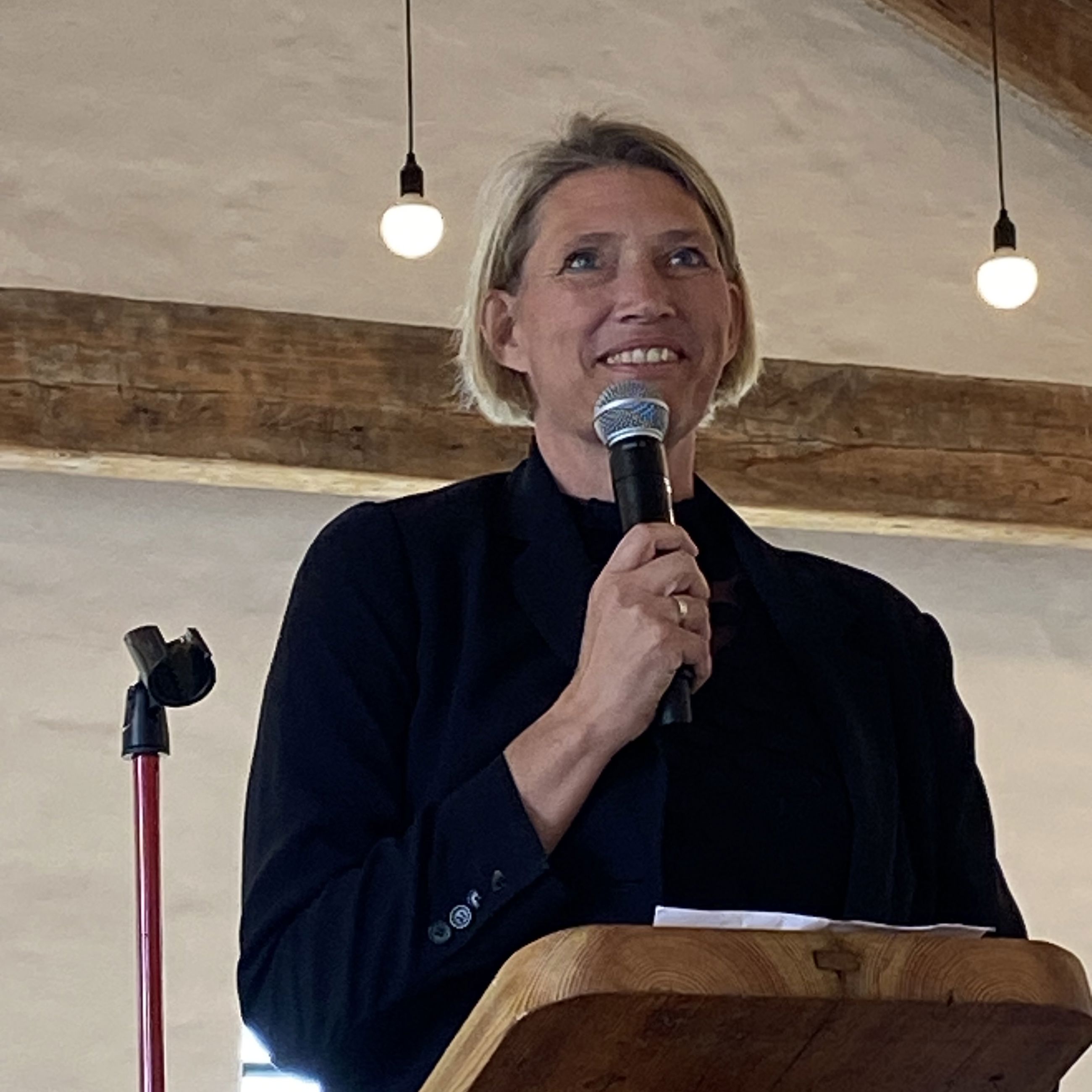 Kvinde står på talerstol og taler i mikrofon