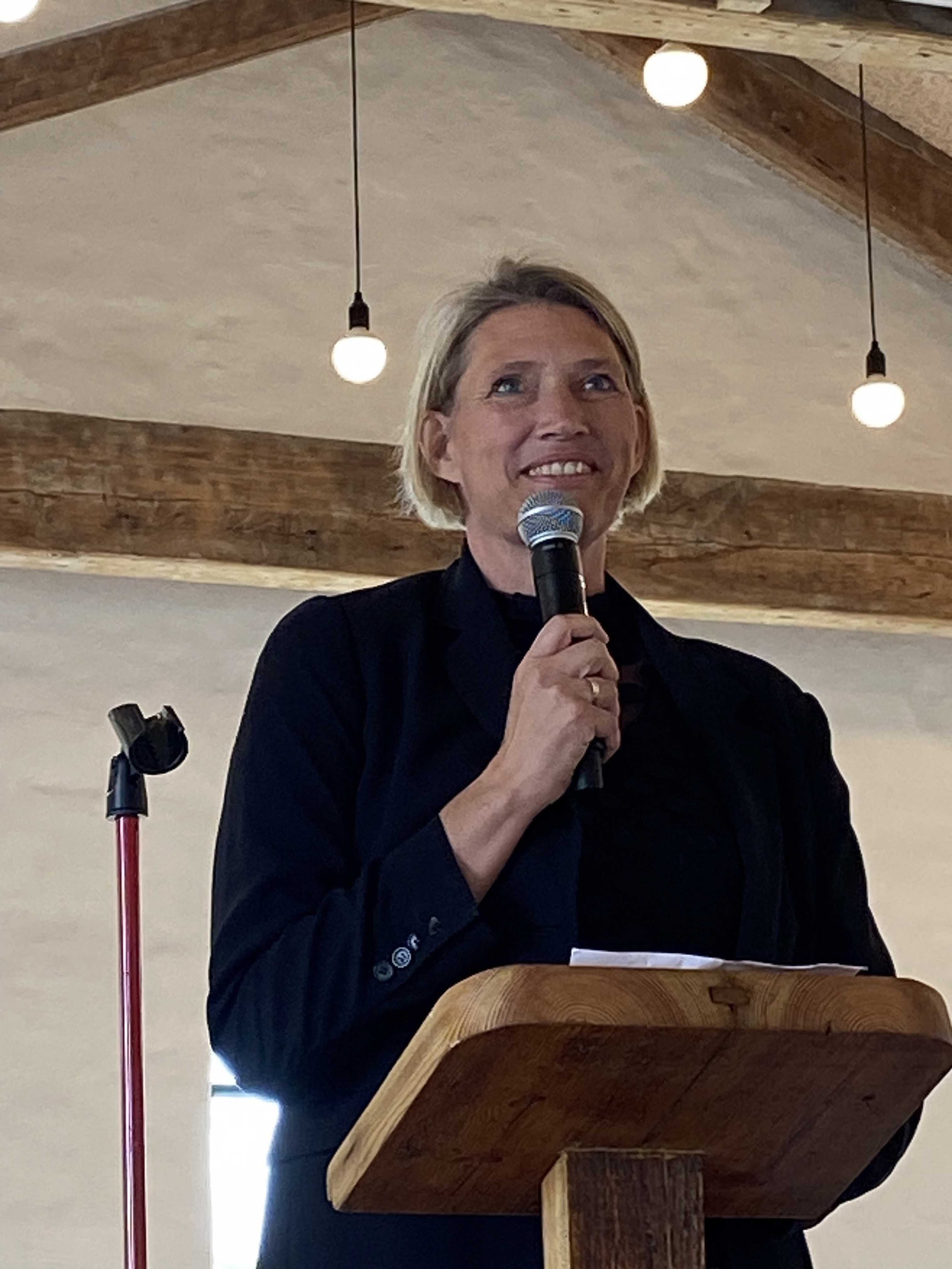 Kvinde står på talerstol og taler i mikrofon