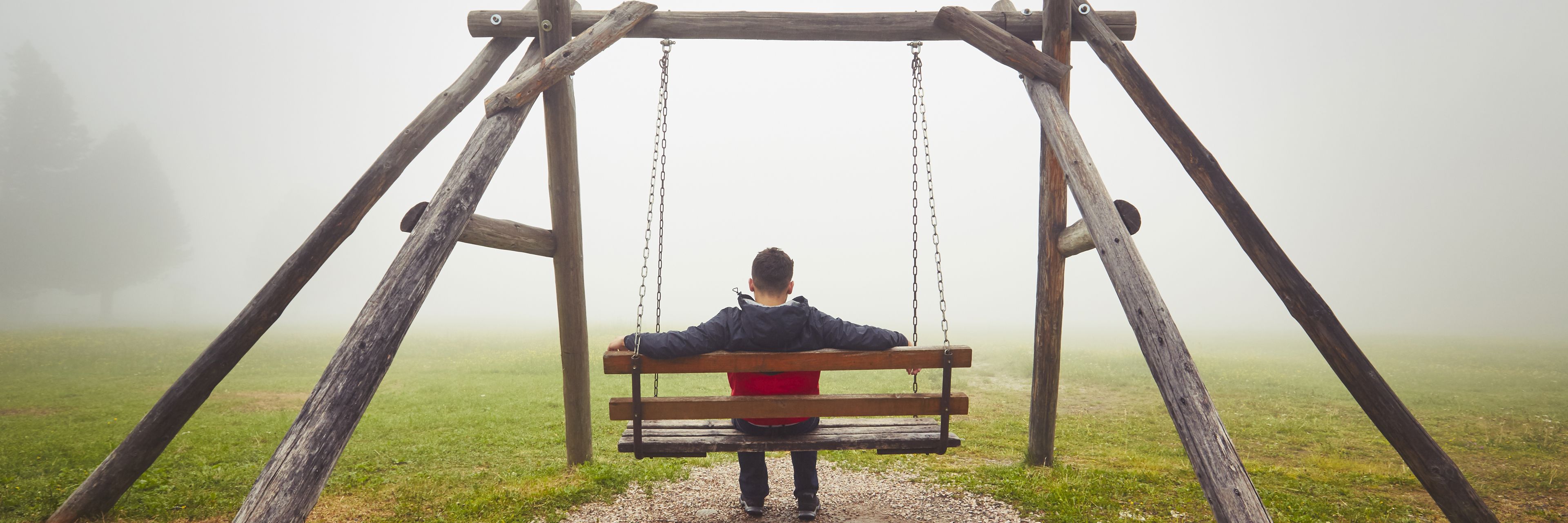 Ung mand sidder alene på gynge