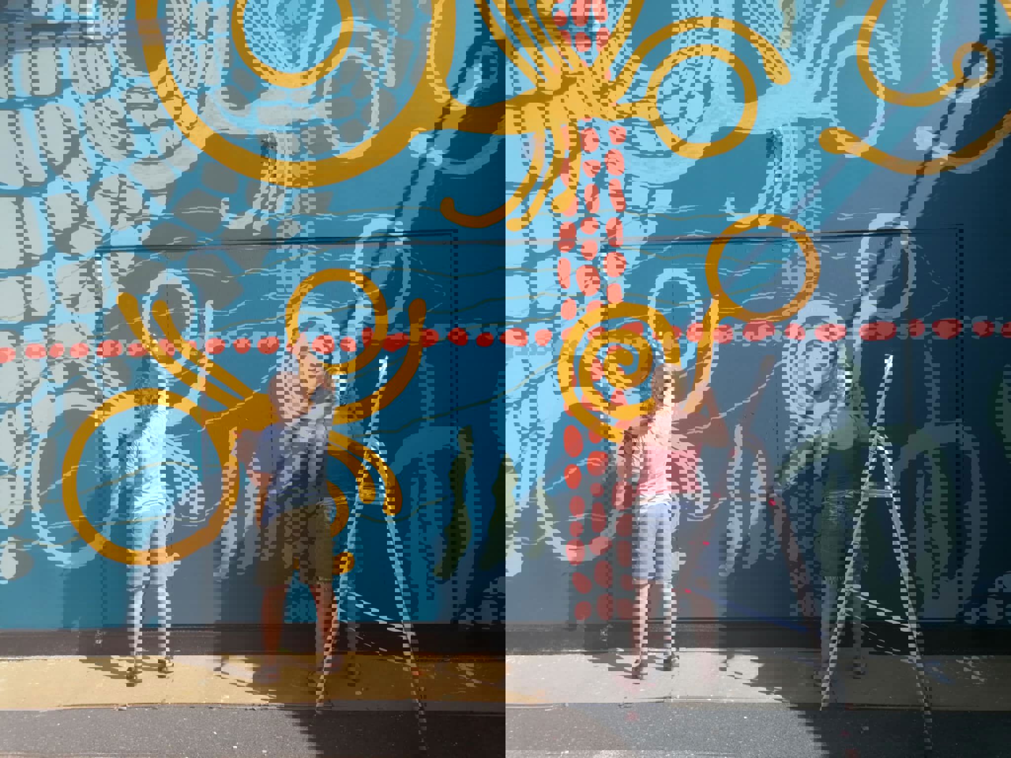 To kvinder maler en ydermur med kunstdekorationer