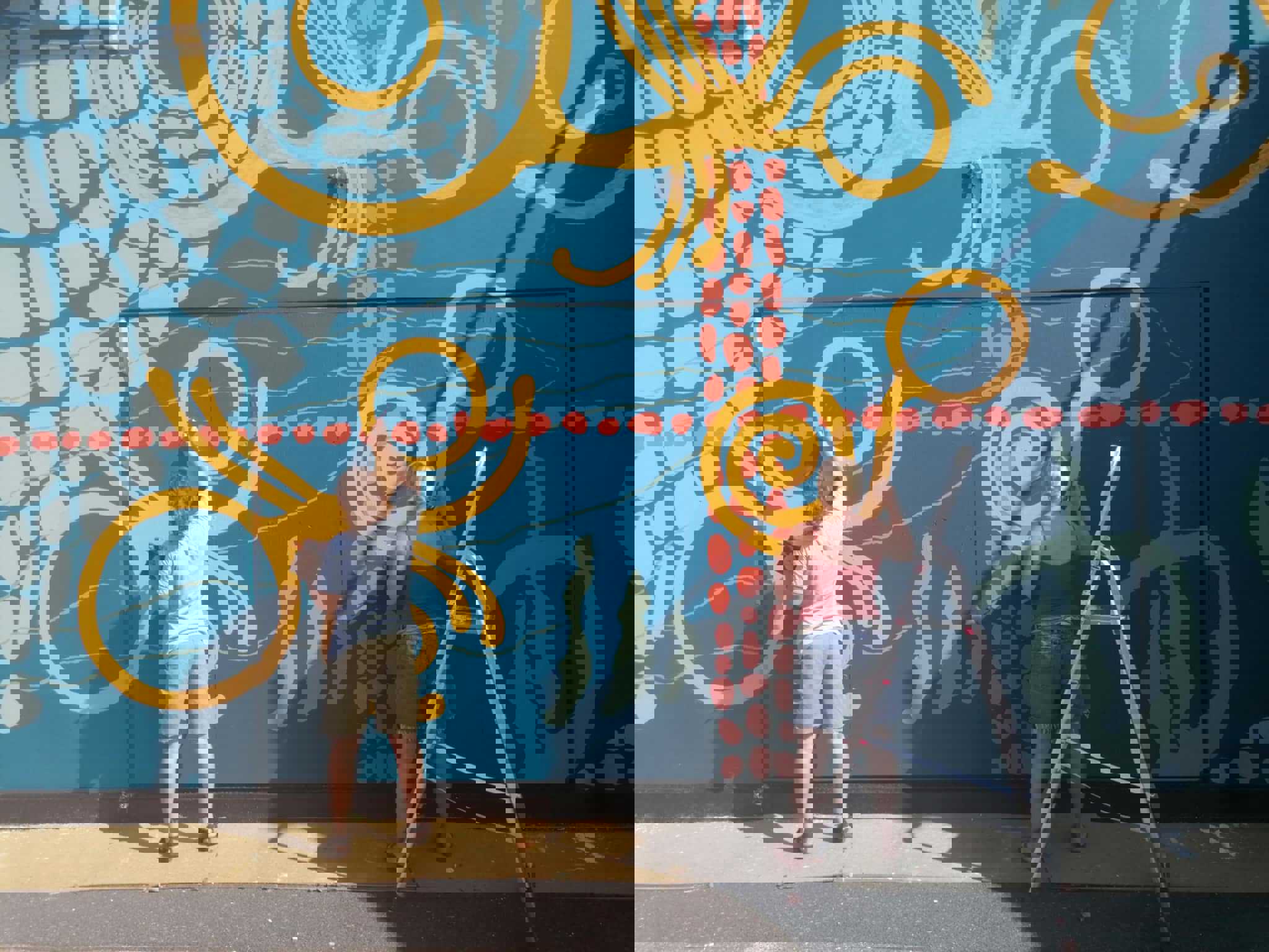 To kvinder maler en ydermur med kunstdekorationer