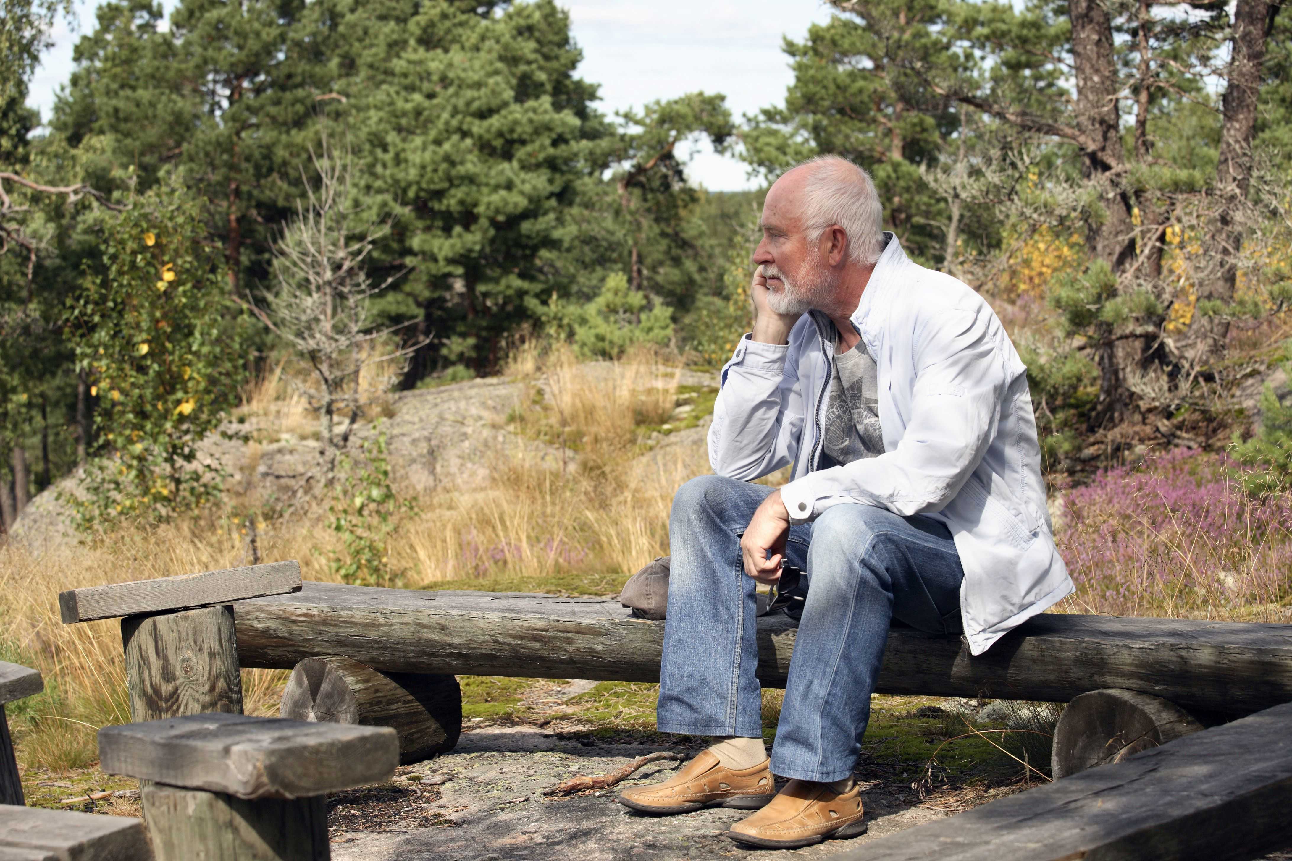 Enlig ældre mand sidder på en bænk