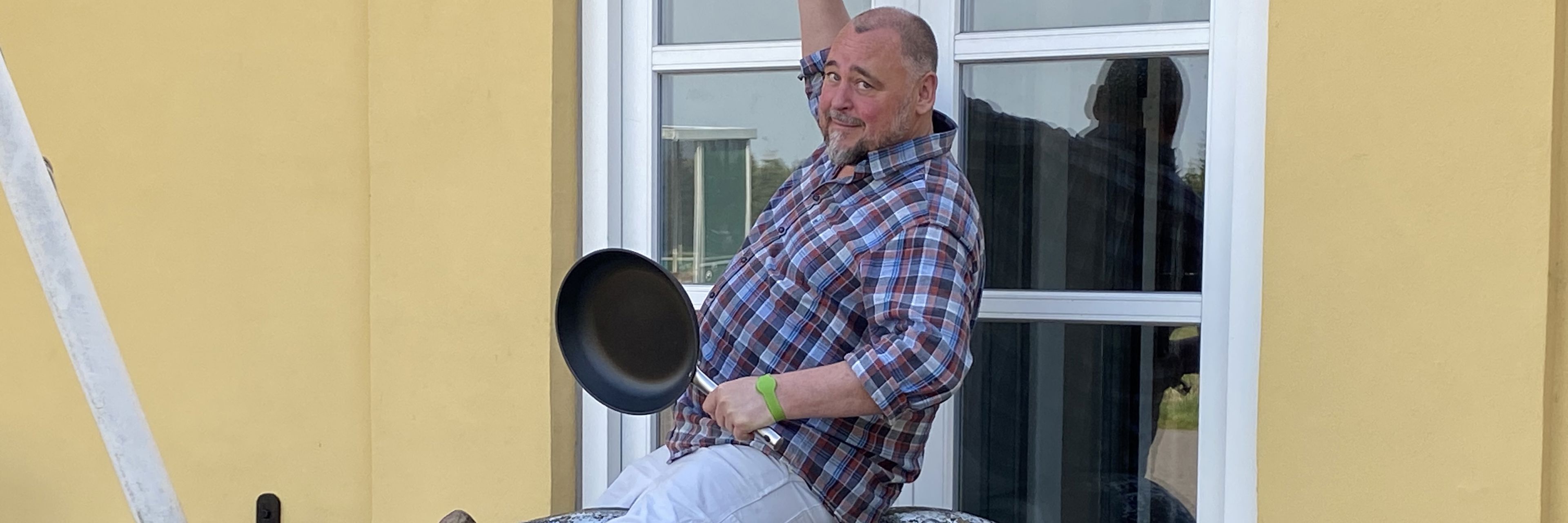 Mand der rider på en plastikgris med en stegepande og en kødkniv i hænderne