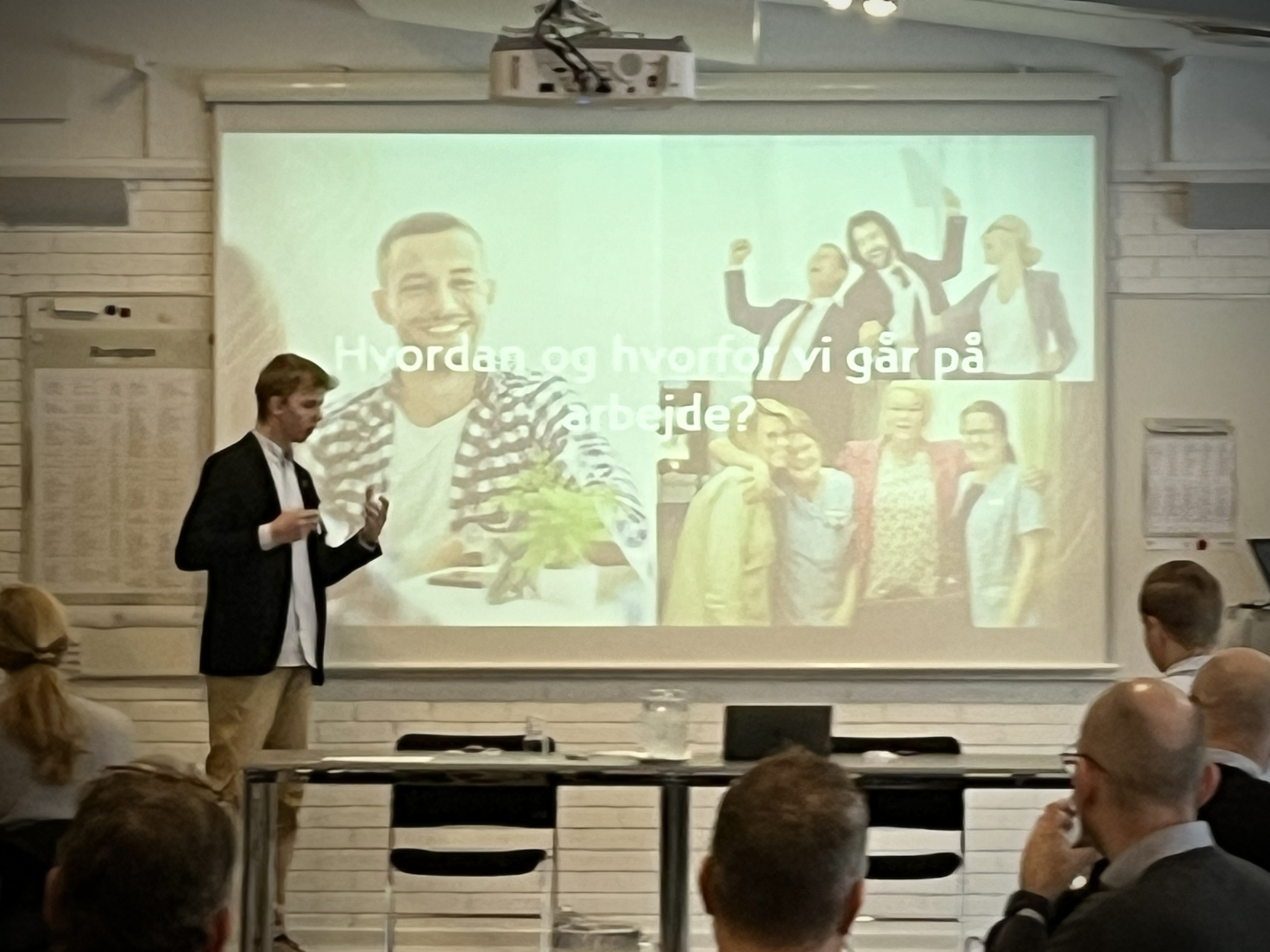 Oplægsholder foran lærred slideshow på erhvervskonference
