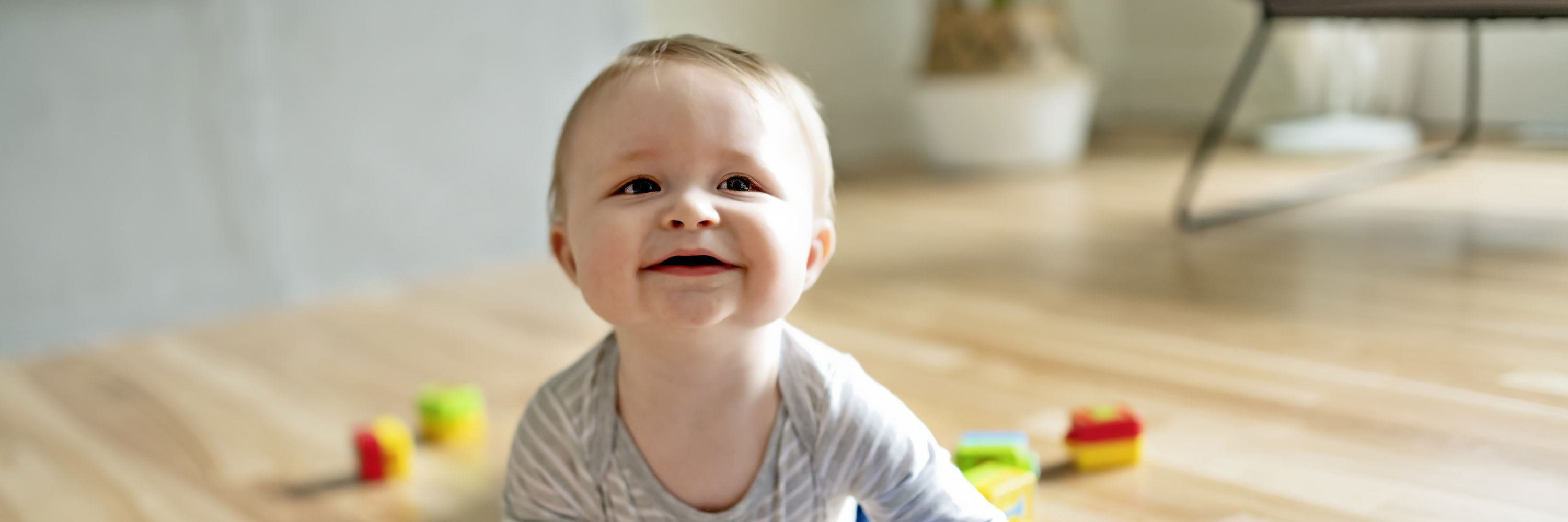 Beby der ligger på et gulv og leger med klodser