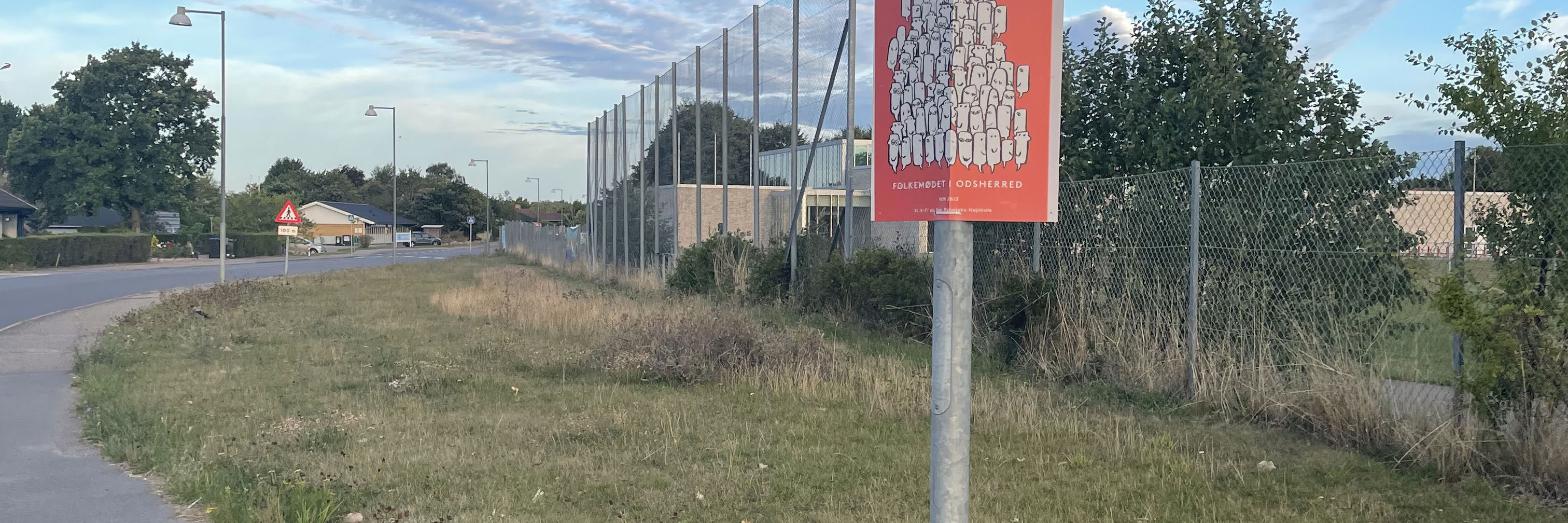 Plakat med reklaem for Folkemødet opsat på lysmast på Nyvej - himen er blå og det er sommer