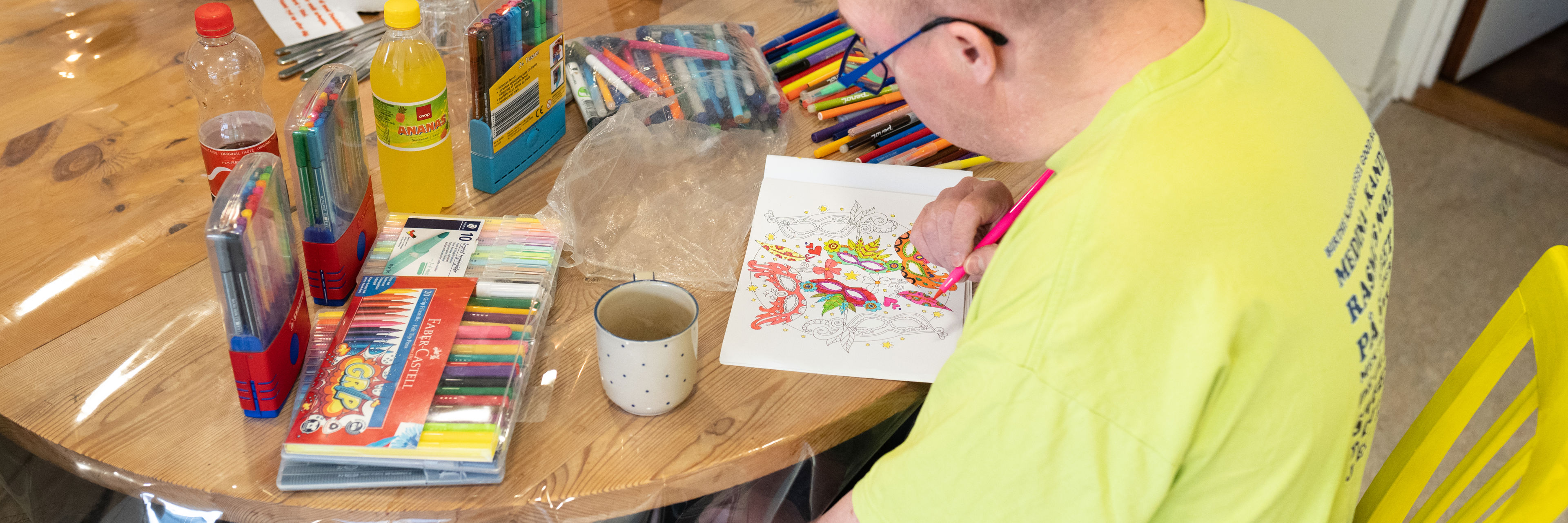 En mand sider og farvelægger et billede