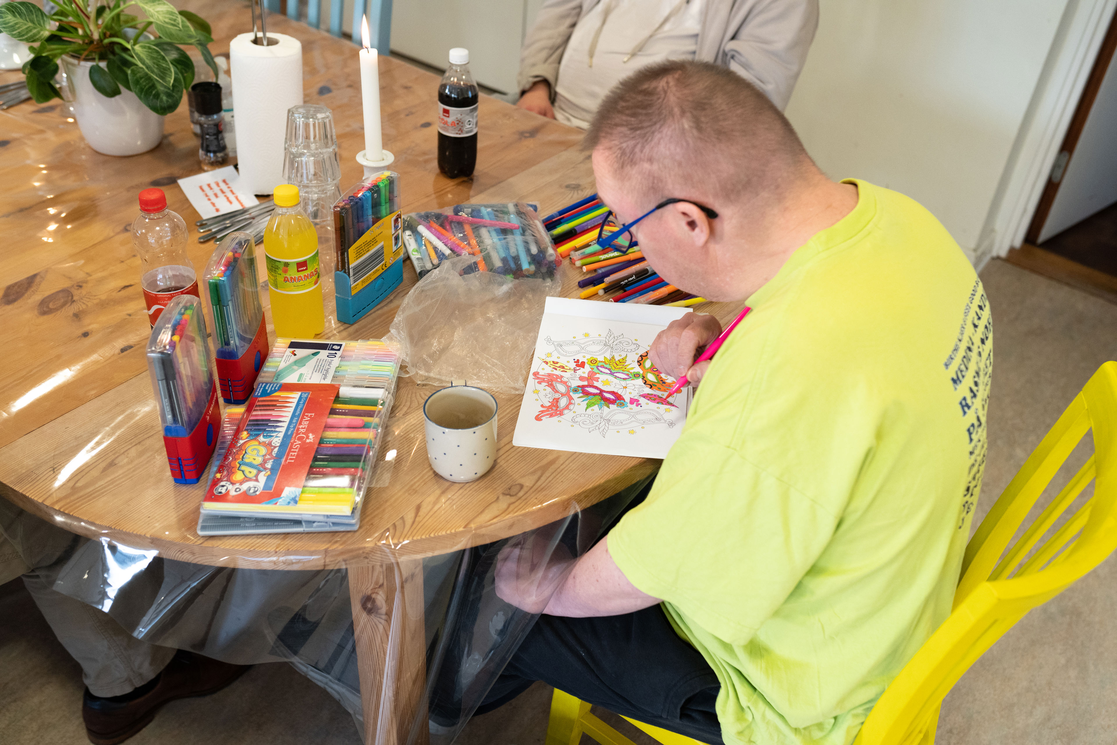 En mand sider og farvelægger et billede