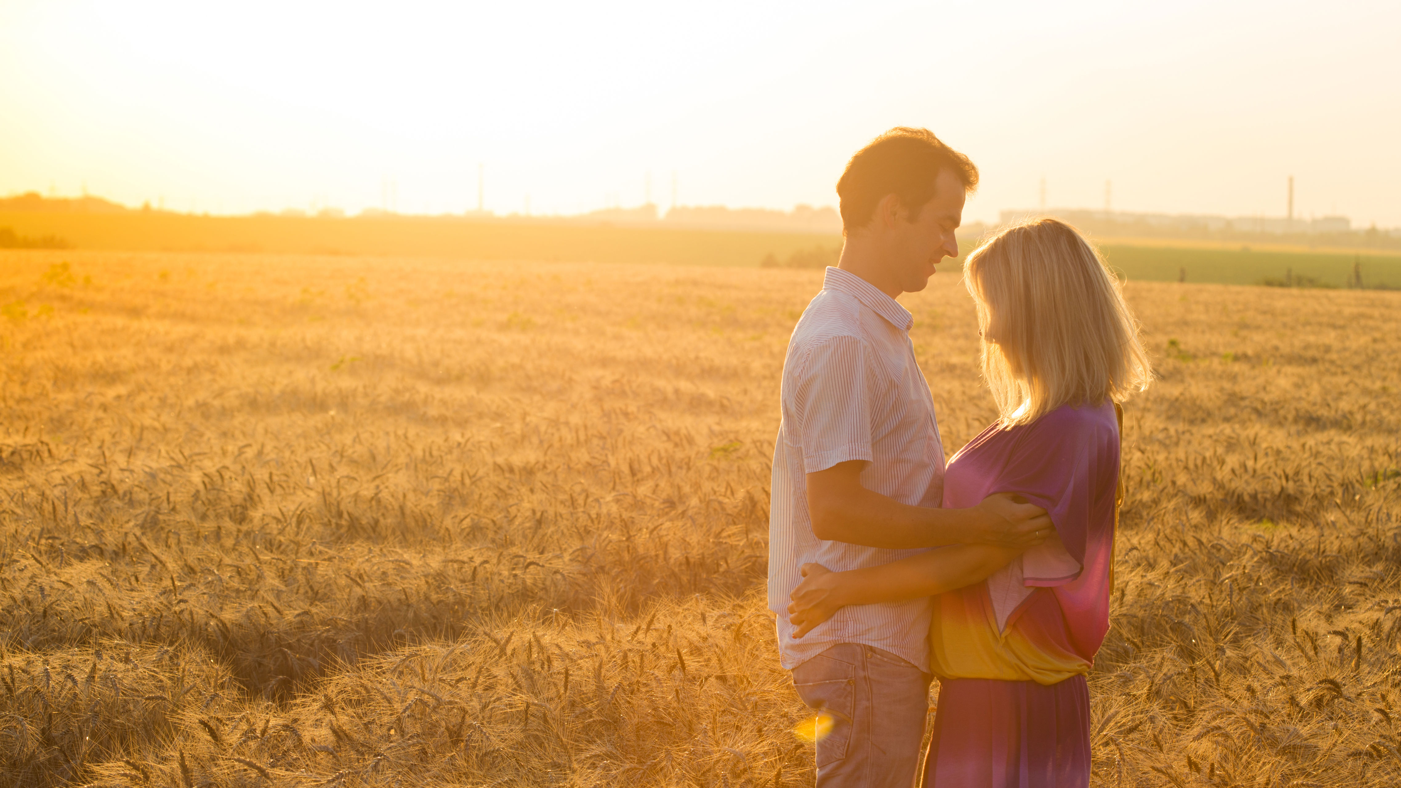 Et par holder om hinden i en kornmark. I solnedgang