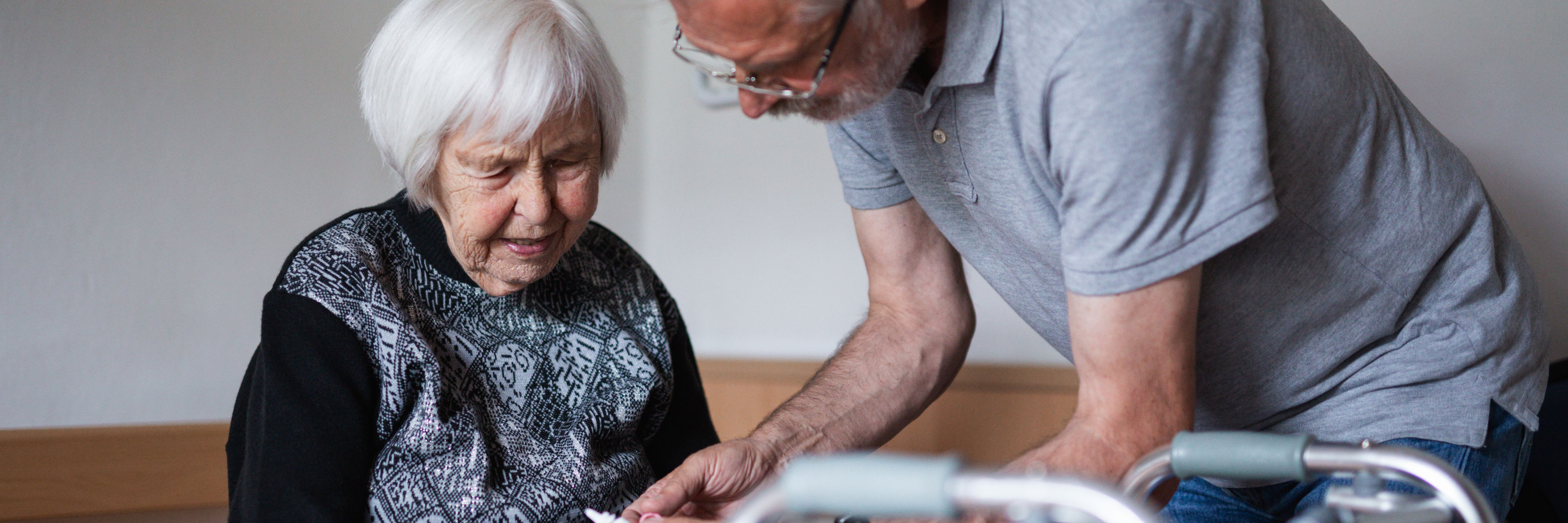 Frivillig mand taler med ældre kvinde, som sidder på en seng med sin rollator foran sig