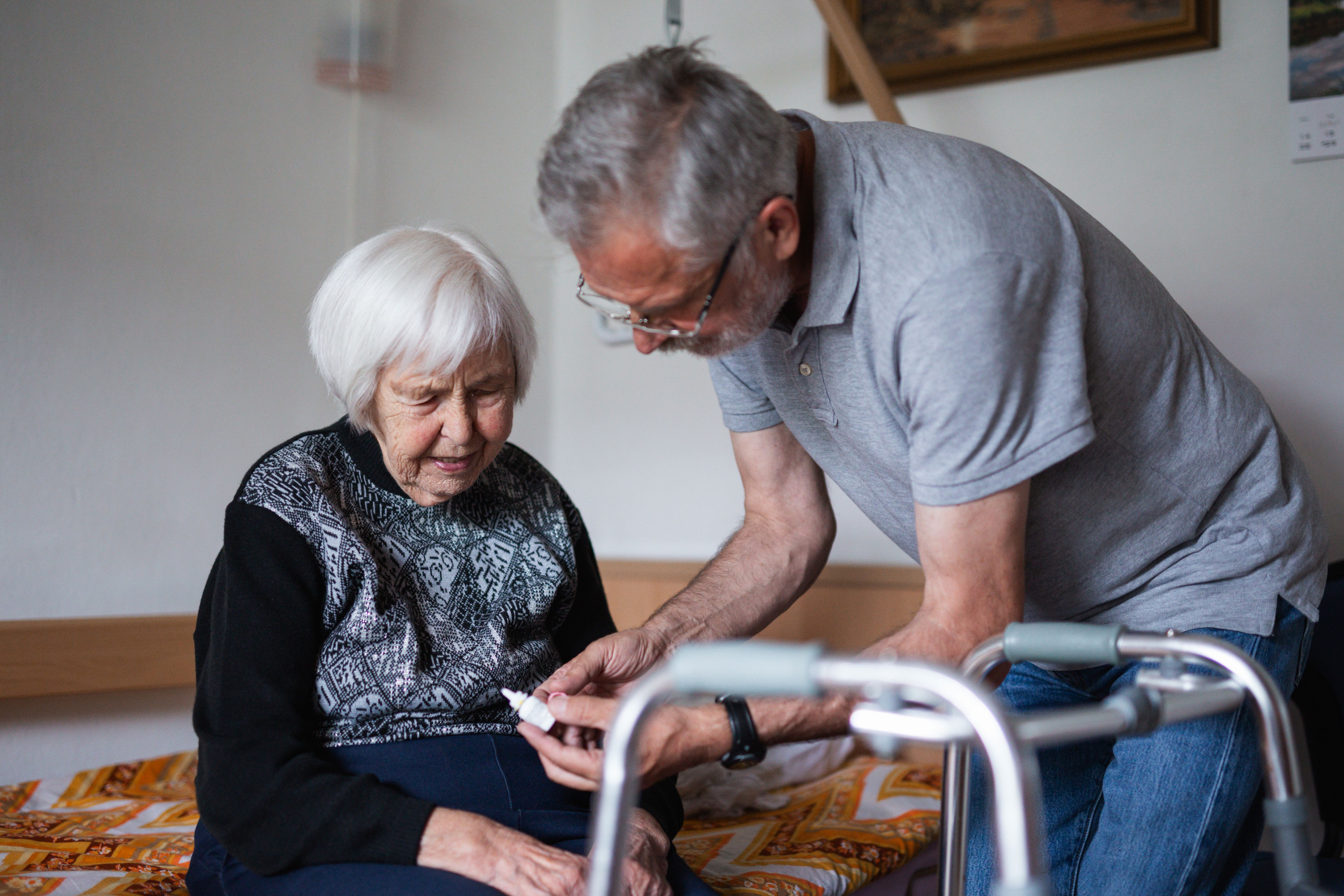 Frivillig mand taler med ældre kvinde, som sidder på en seng med sin rollator foran sig