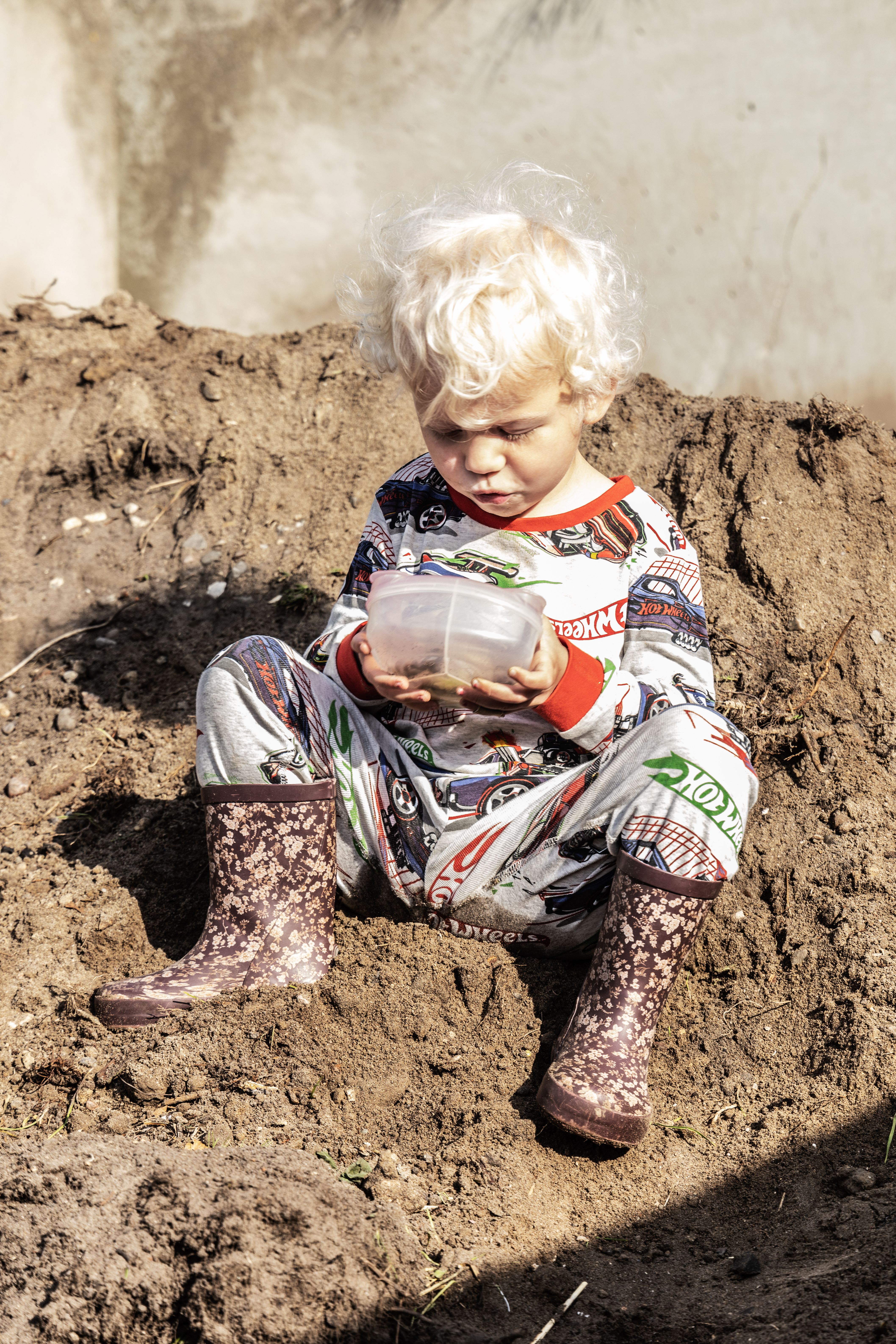Barn sidder i jordbunke på genbrugsstationen
