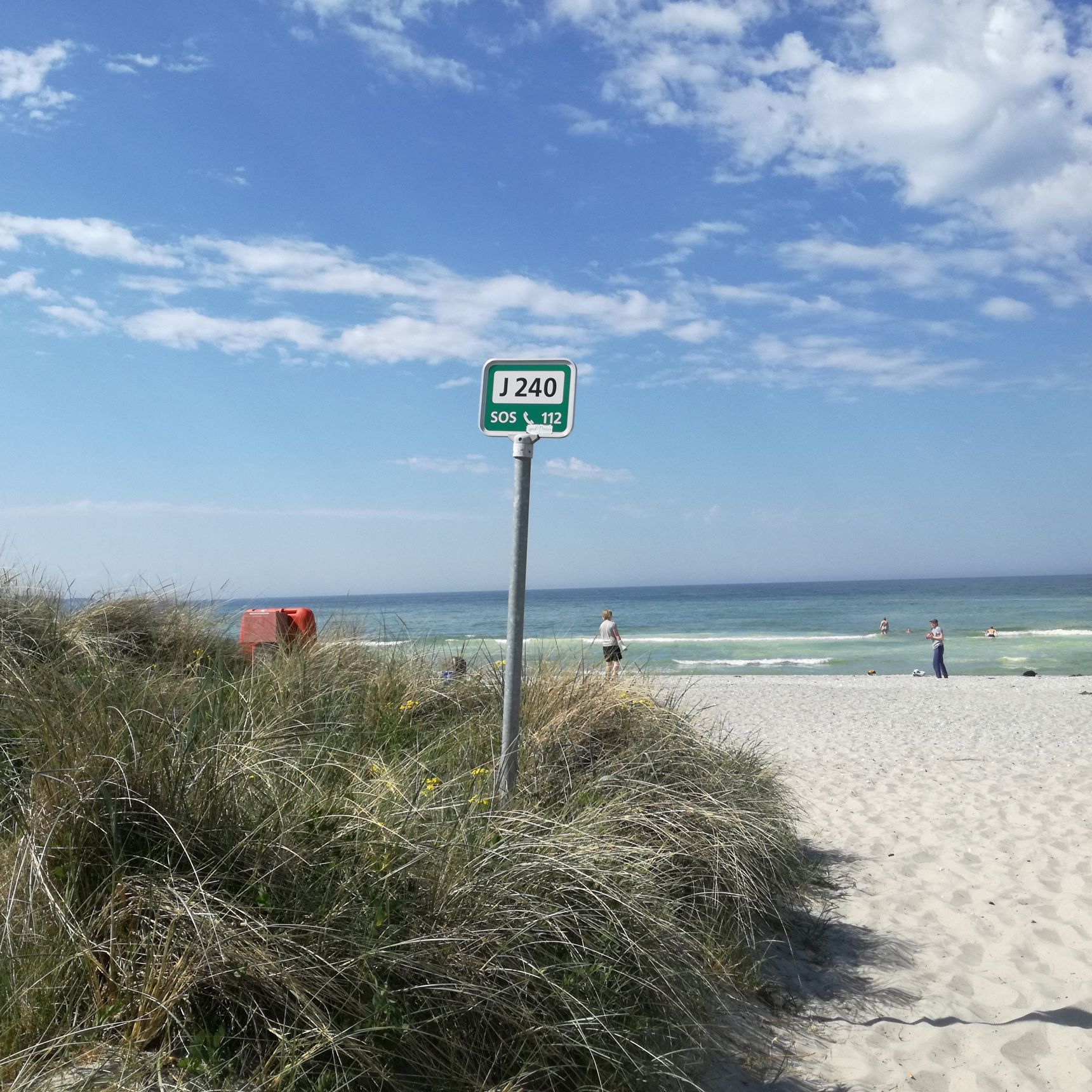 Skilt med redningsnummer på strand