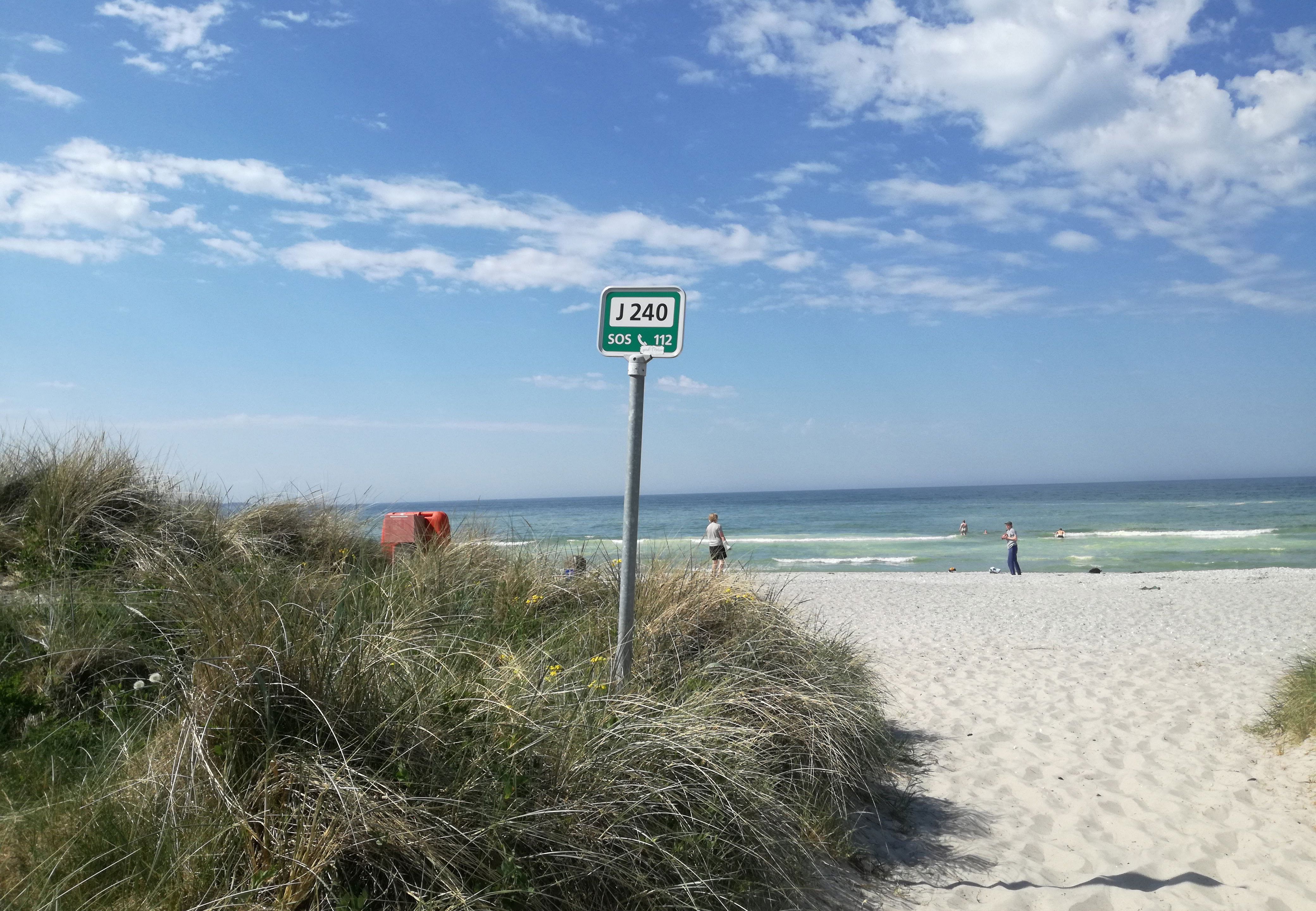 Skilt med redningsnummer på strand
