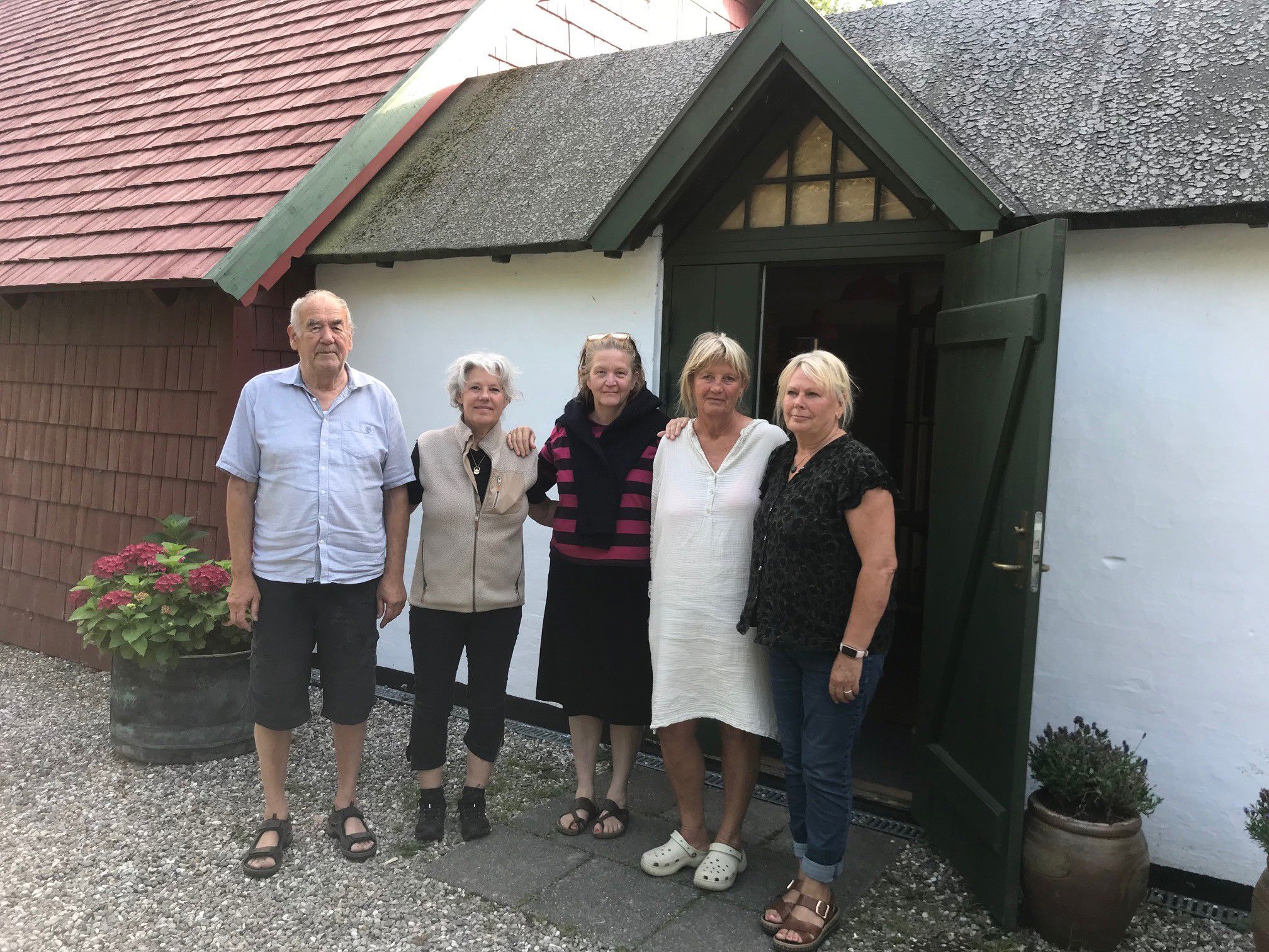 En gruppe mennesker står foran et gammelt hus