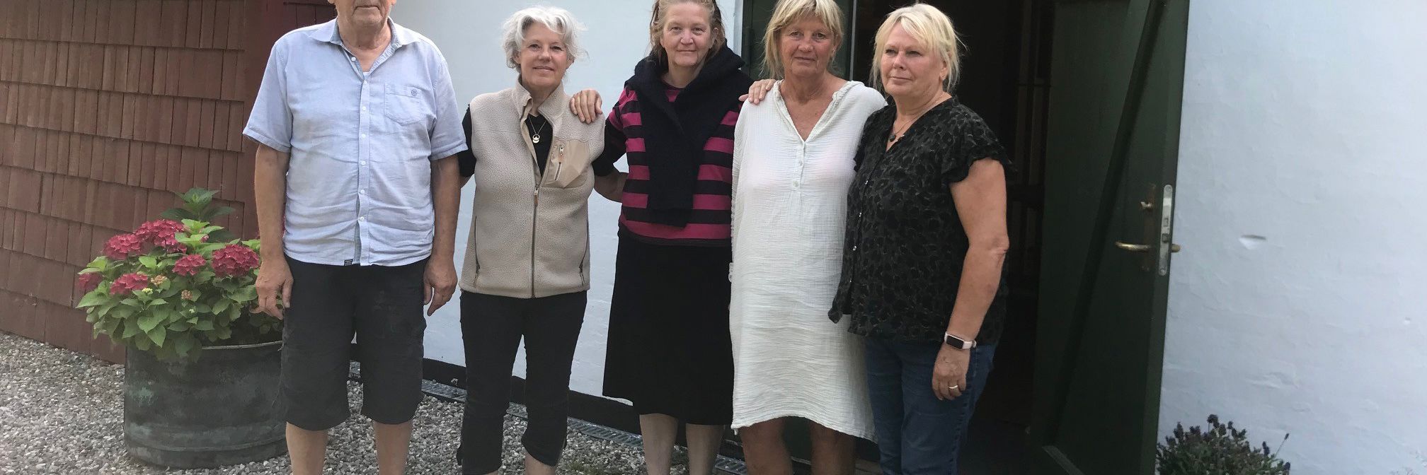 En gruppe mennesker står foran et gammelt hus