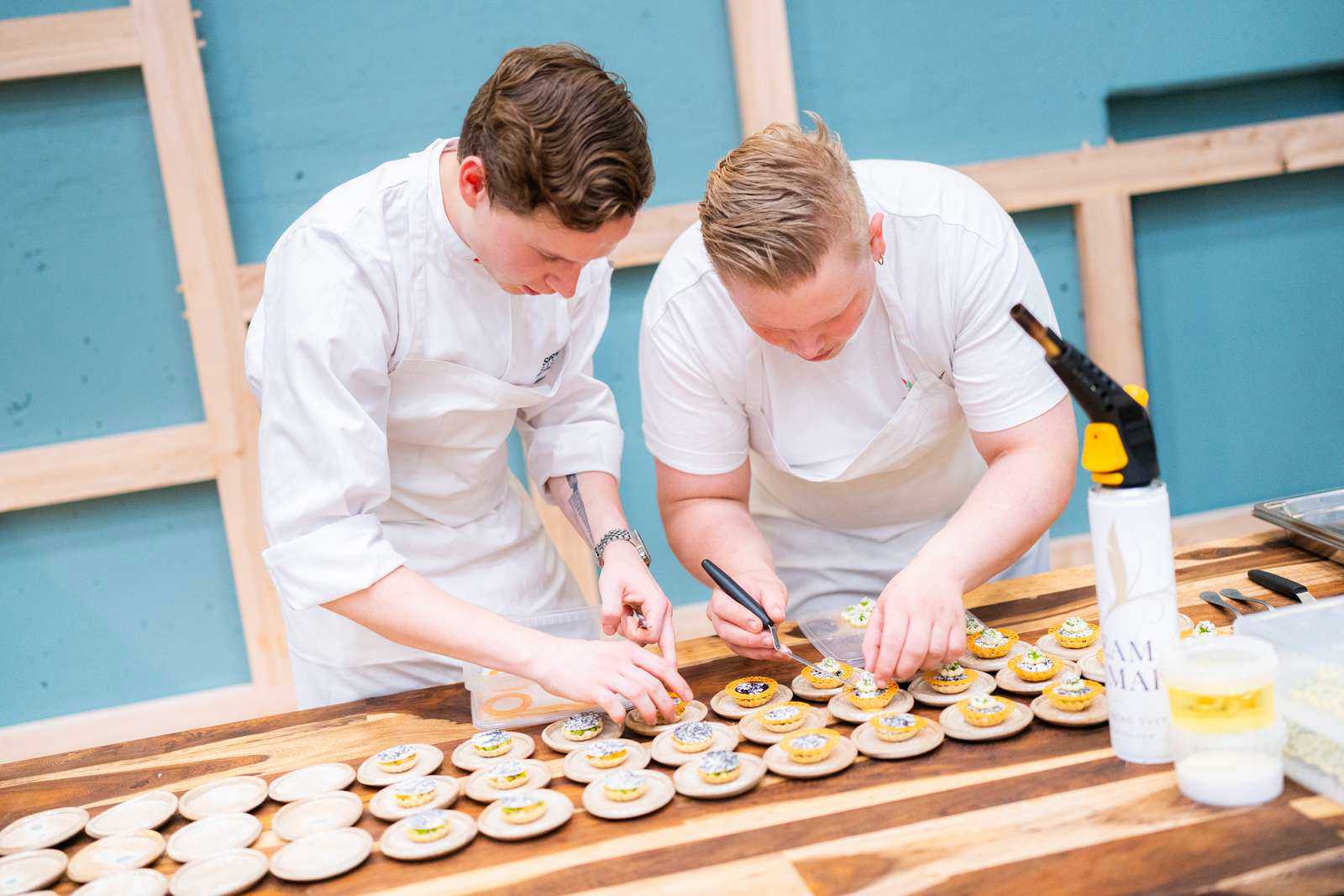 To kokke står bøjet over anretterbordet