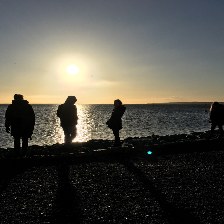 Unge mennesker ved havet ved solopgang