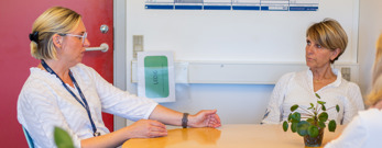 Tre personer sidder ved et bord og taler