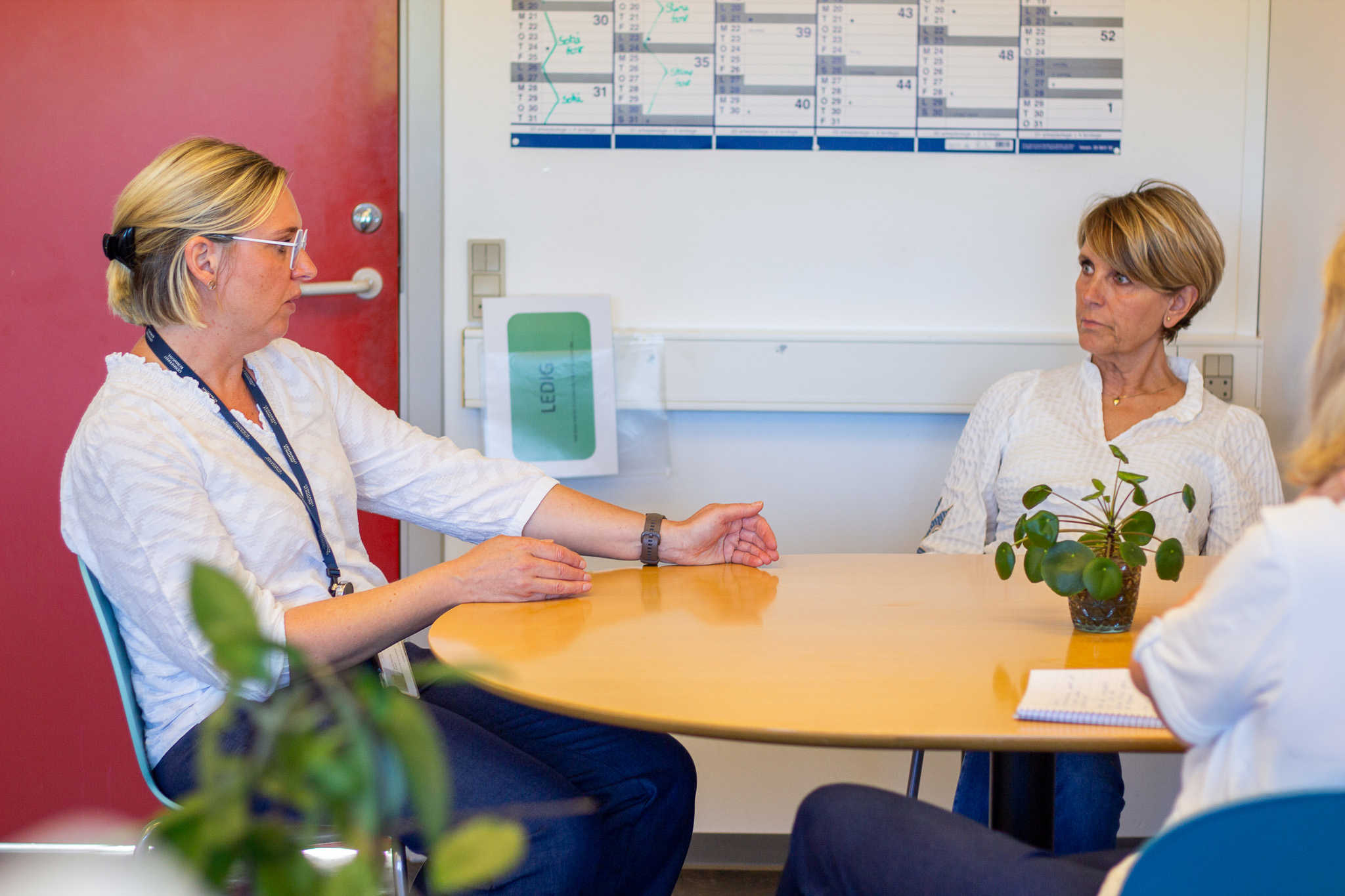 Tre personer sidder ved et bord og taler