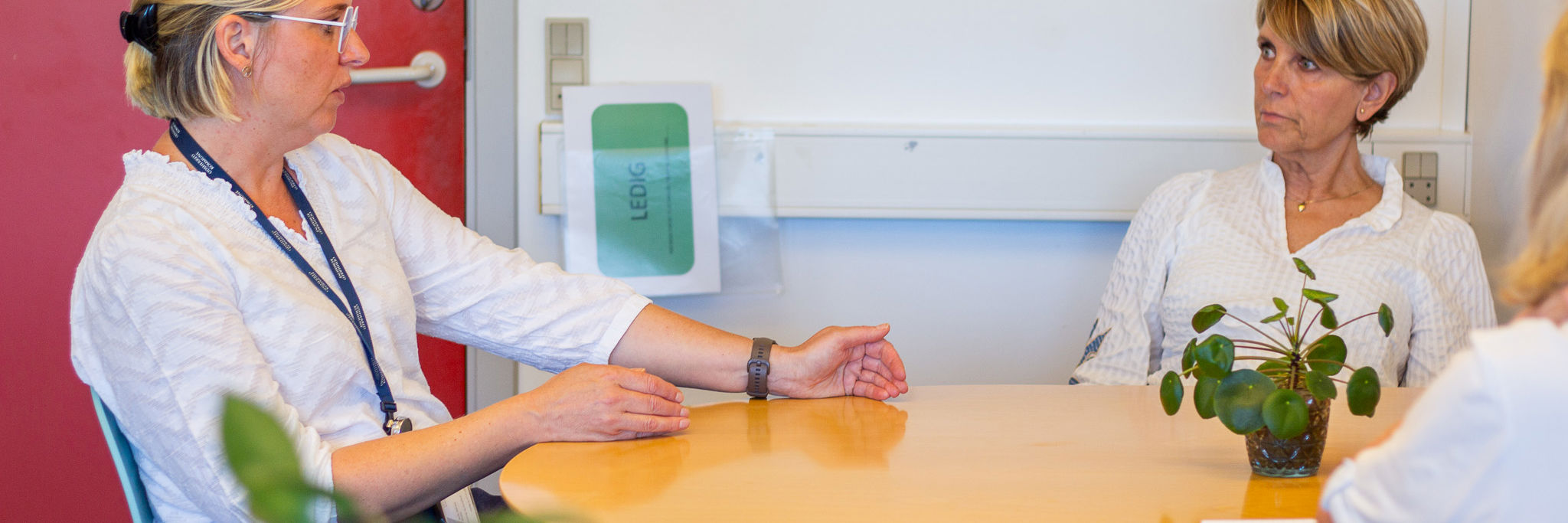 Tre personer sidder ved et bord og taler