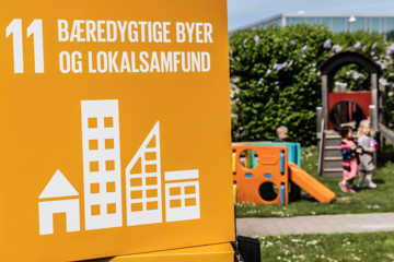 Verdensmål 11: Bæredygtige byer og lokalsamfund. Børn i baggrunden