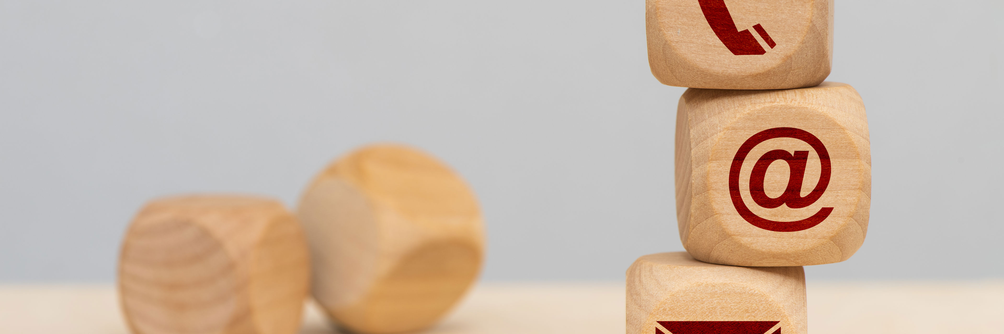 Tre terninger med hhv. en telefon, et snabel-a og en kuvert stablet oven på hinanden