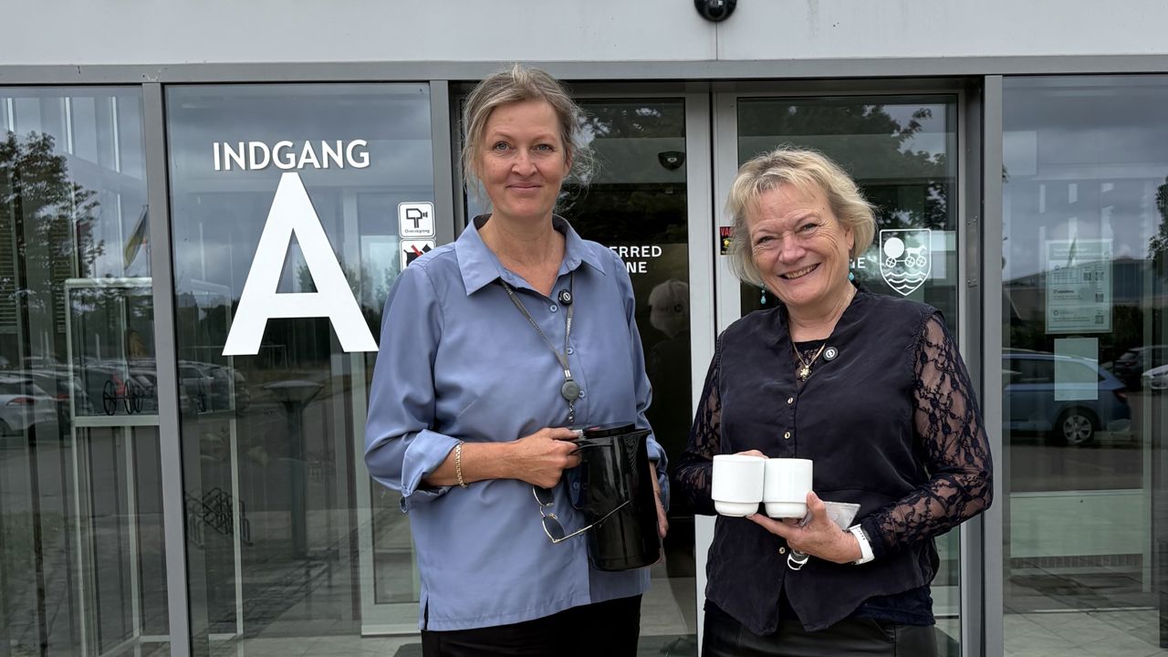 Kommunaldirektør Mette Touborg og borgmester Hanne Pigonska foran rådhuset med en termokande og to kopper