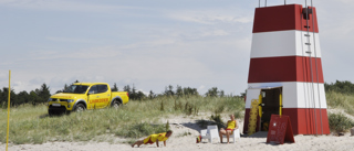 Stranden med rødt/hvidt livreddertårn med gul pickup i baggrunden