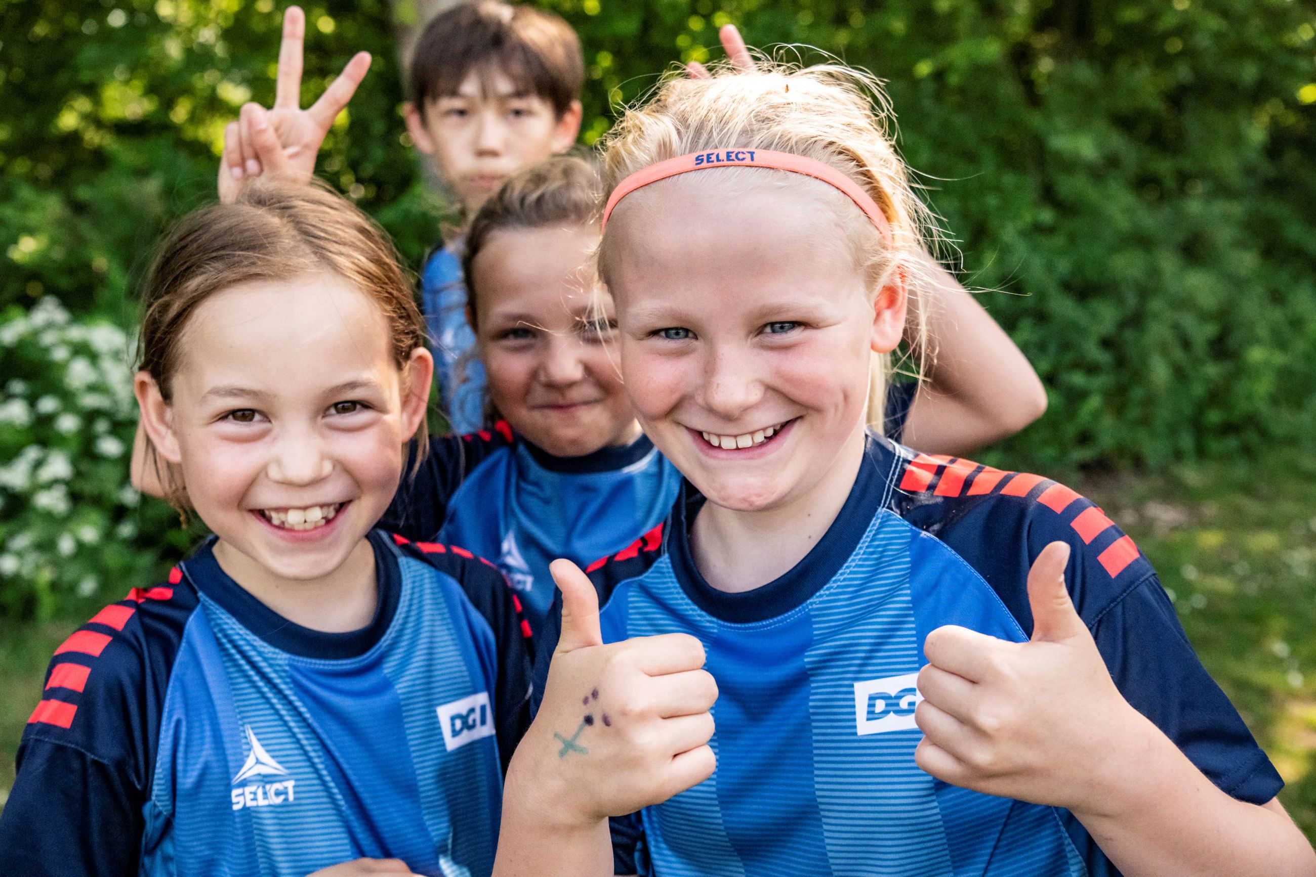 Smilende børn på fodboldskole giver thumps up