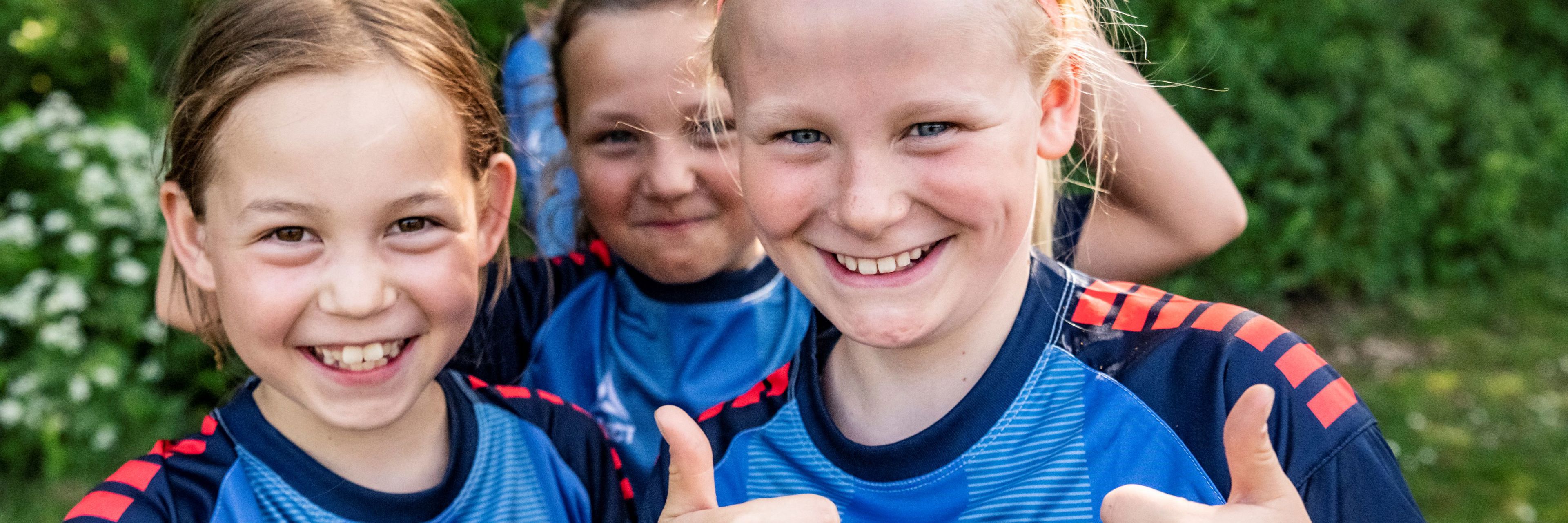 Smilende børn på fodboldskole giver thumps up