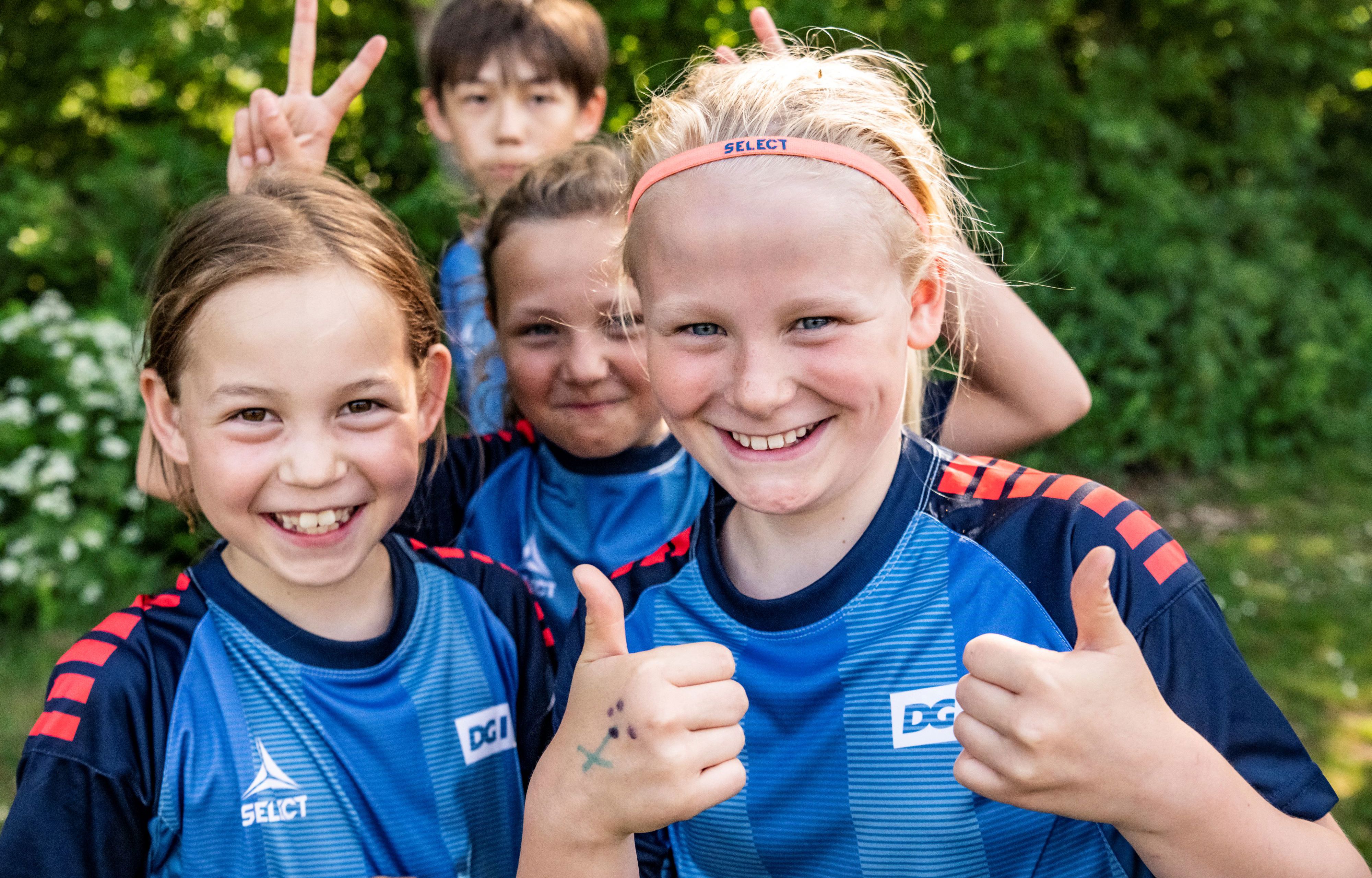 Smilende børn på fodboldskole giver thumps up