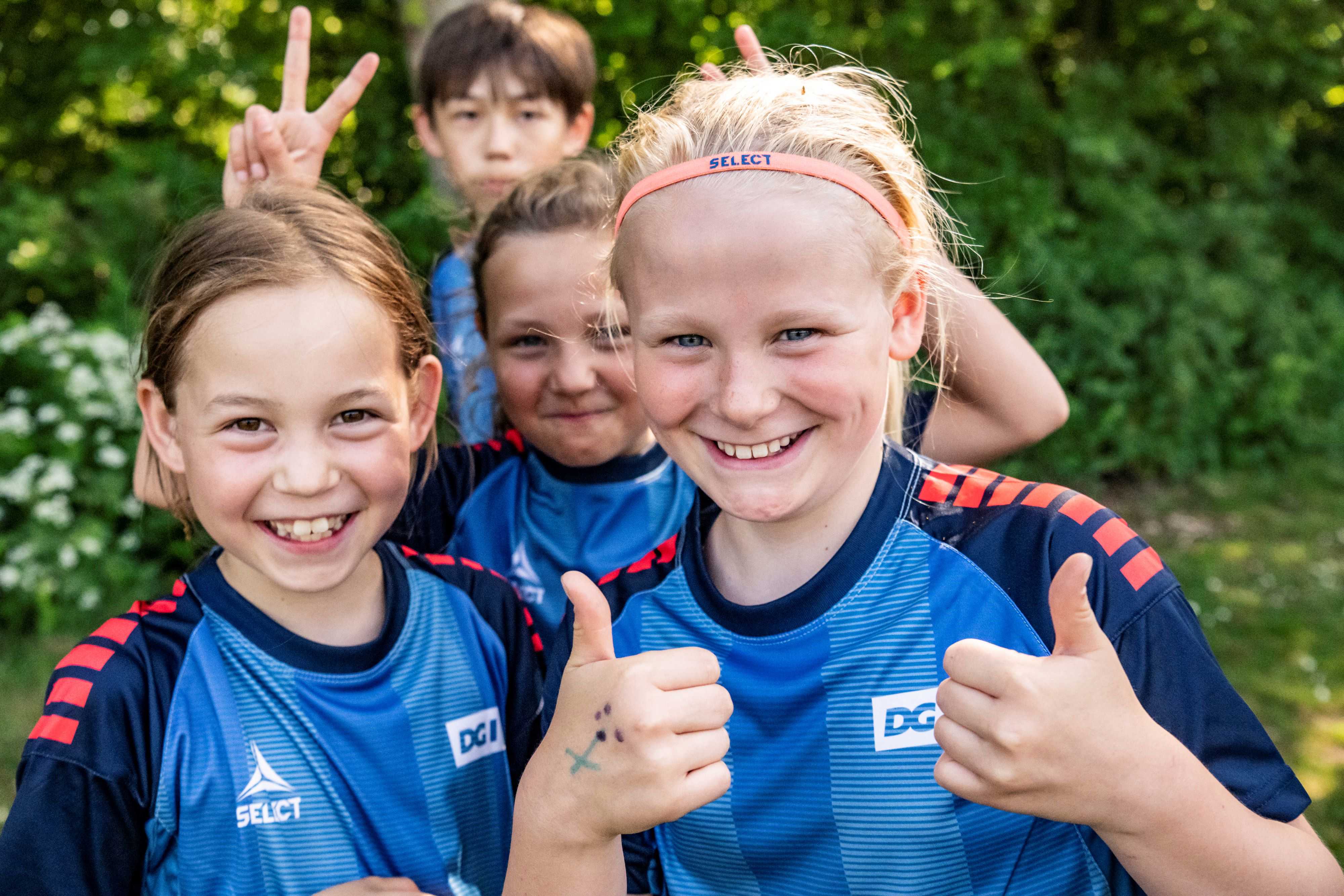 Smilende børn på fodboldskole giver thumps up