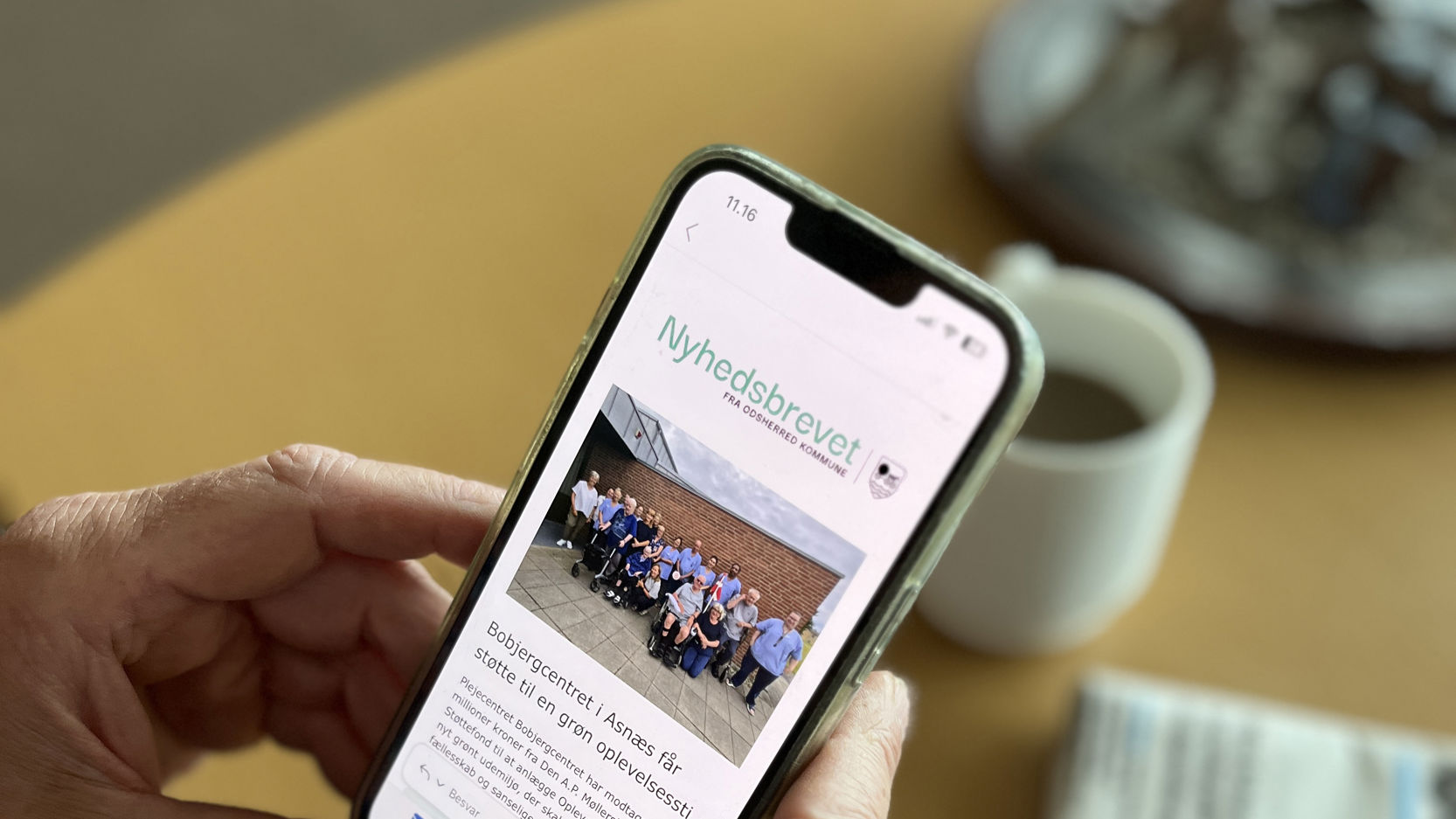 En person læser nyhedsbrevet fra Odsherred Kommune på sin telefon