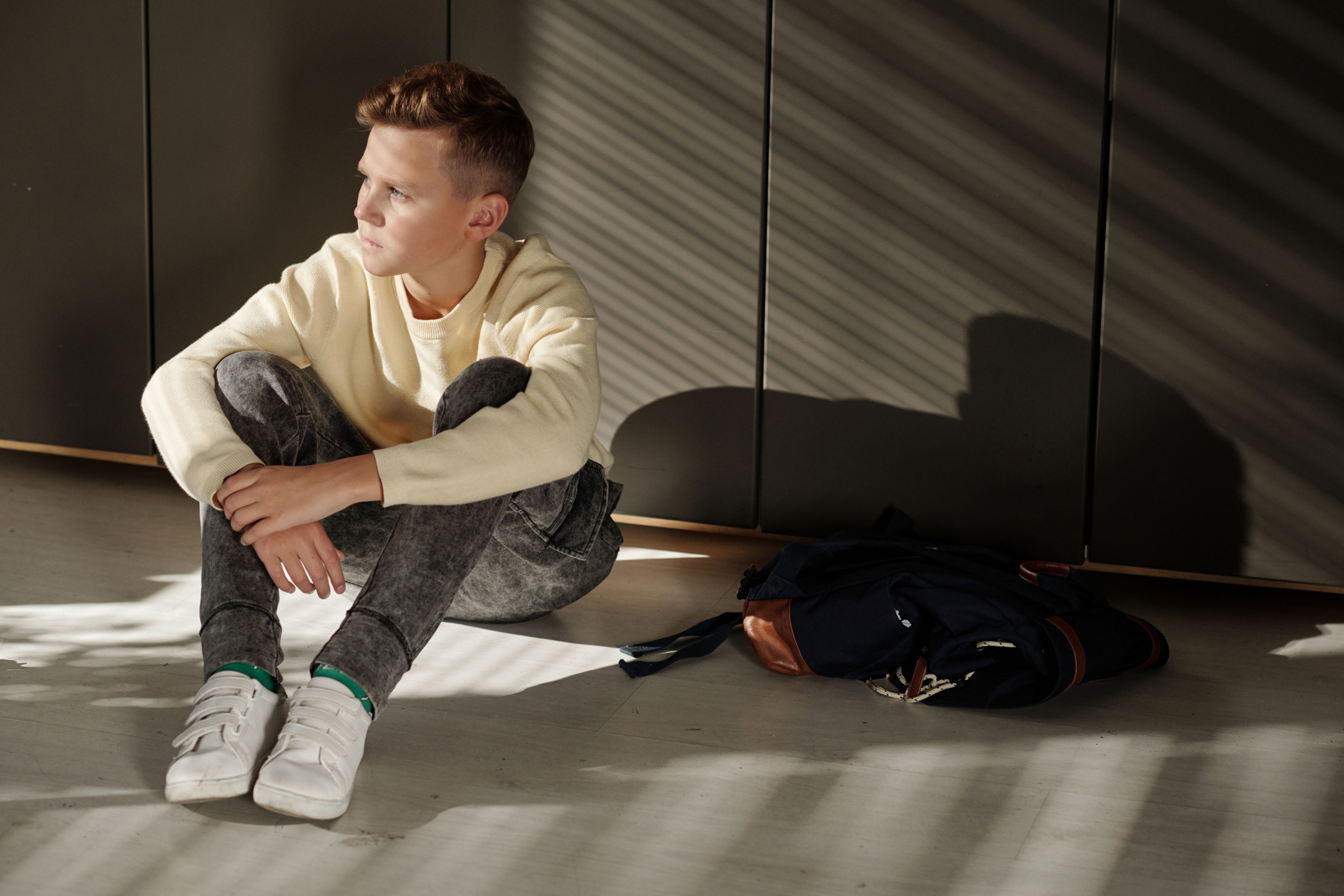 Dreng der sidder på gulvet og ser trist ud