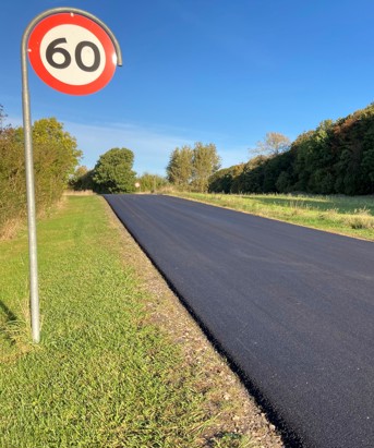 Nyasfalteret vej, stadig uden striber, ved nyklippede græsrabatter